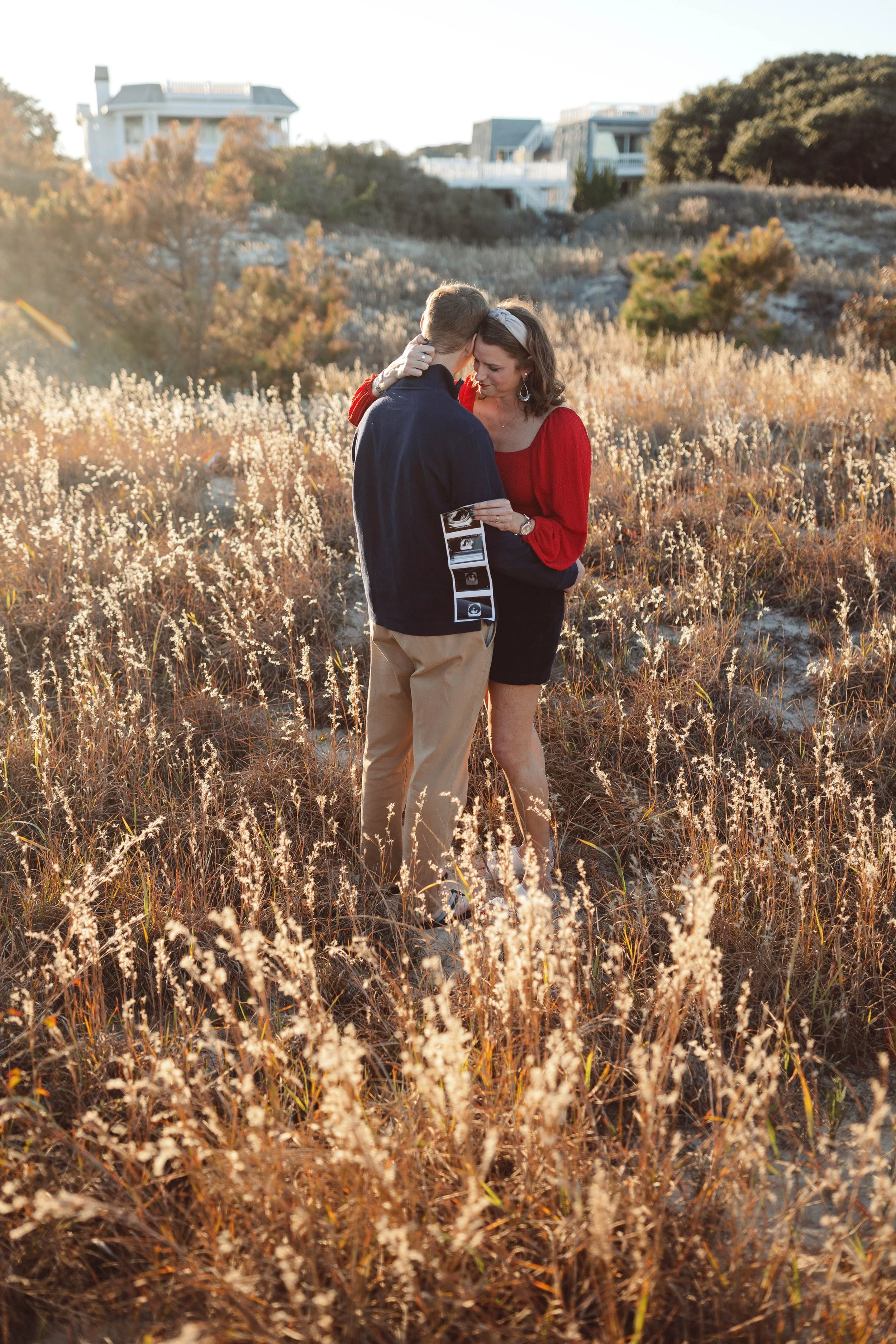 virginia beach navy couple holds miracle baby onesie standing at virginia beach north end