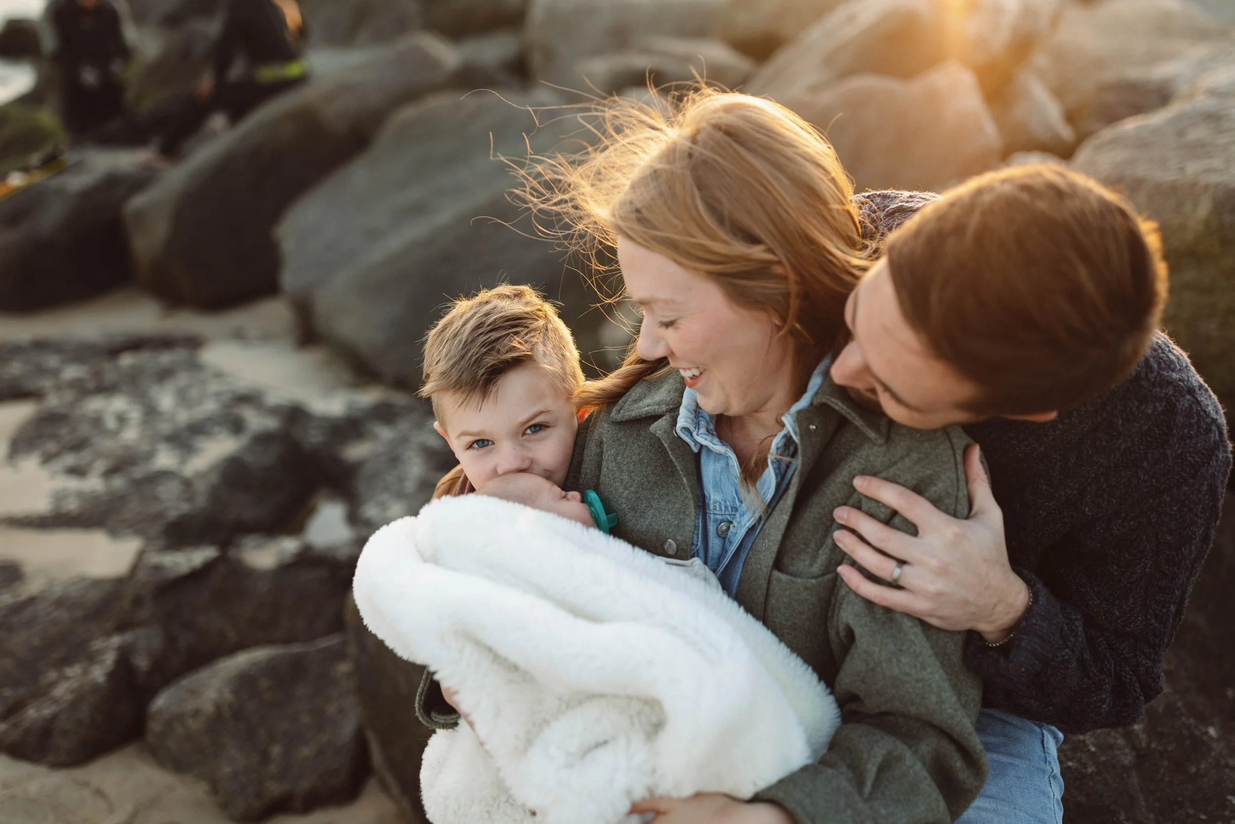 Parents sitting on the rocks with their two children during a sunrise photo session