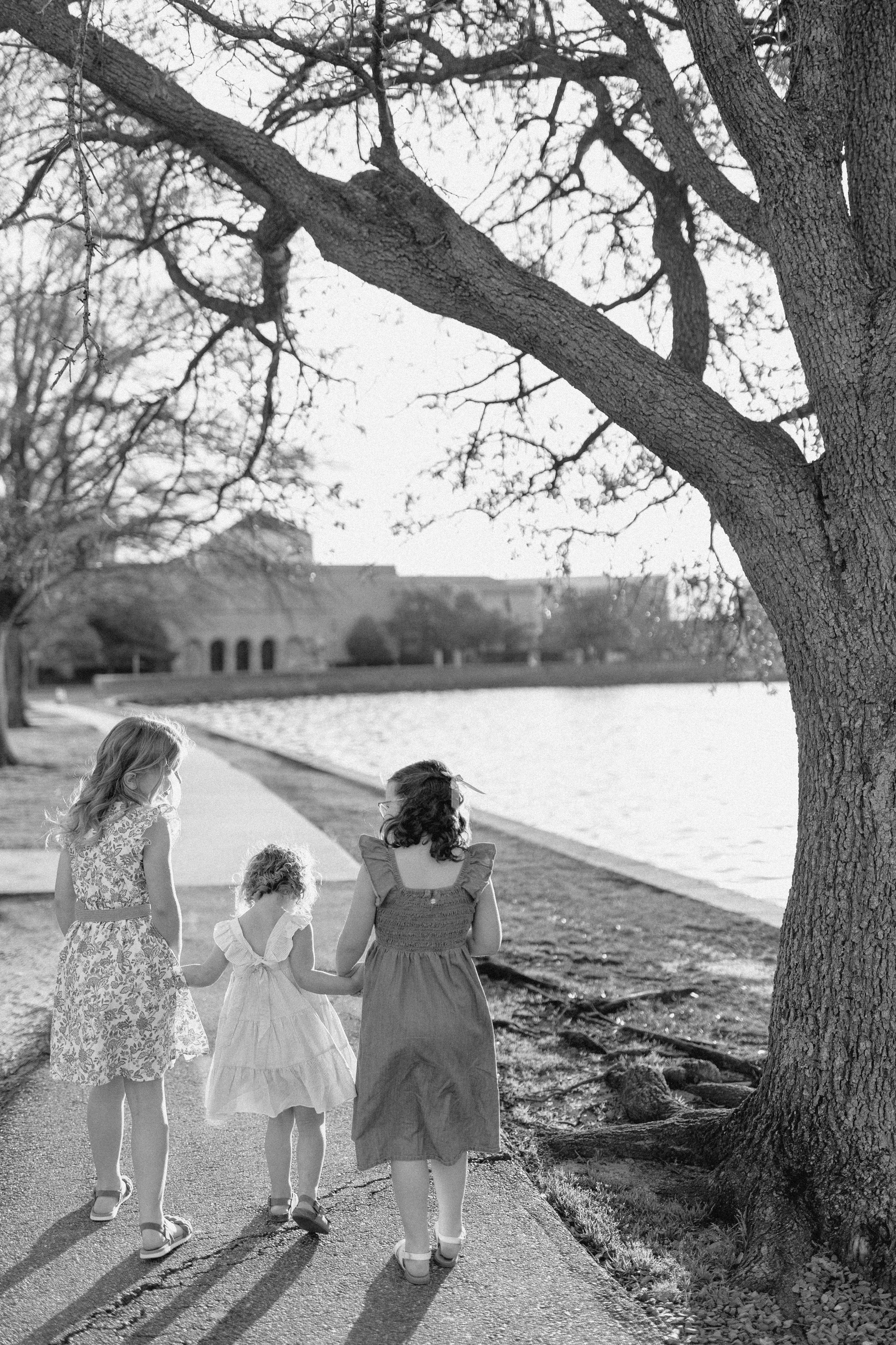 three girls walk side by side along walkway toward Chrysler museum along Hague in Norfolk Virginia