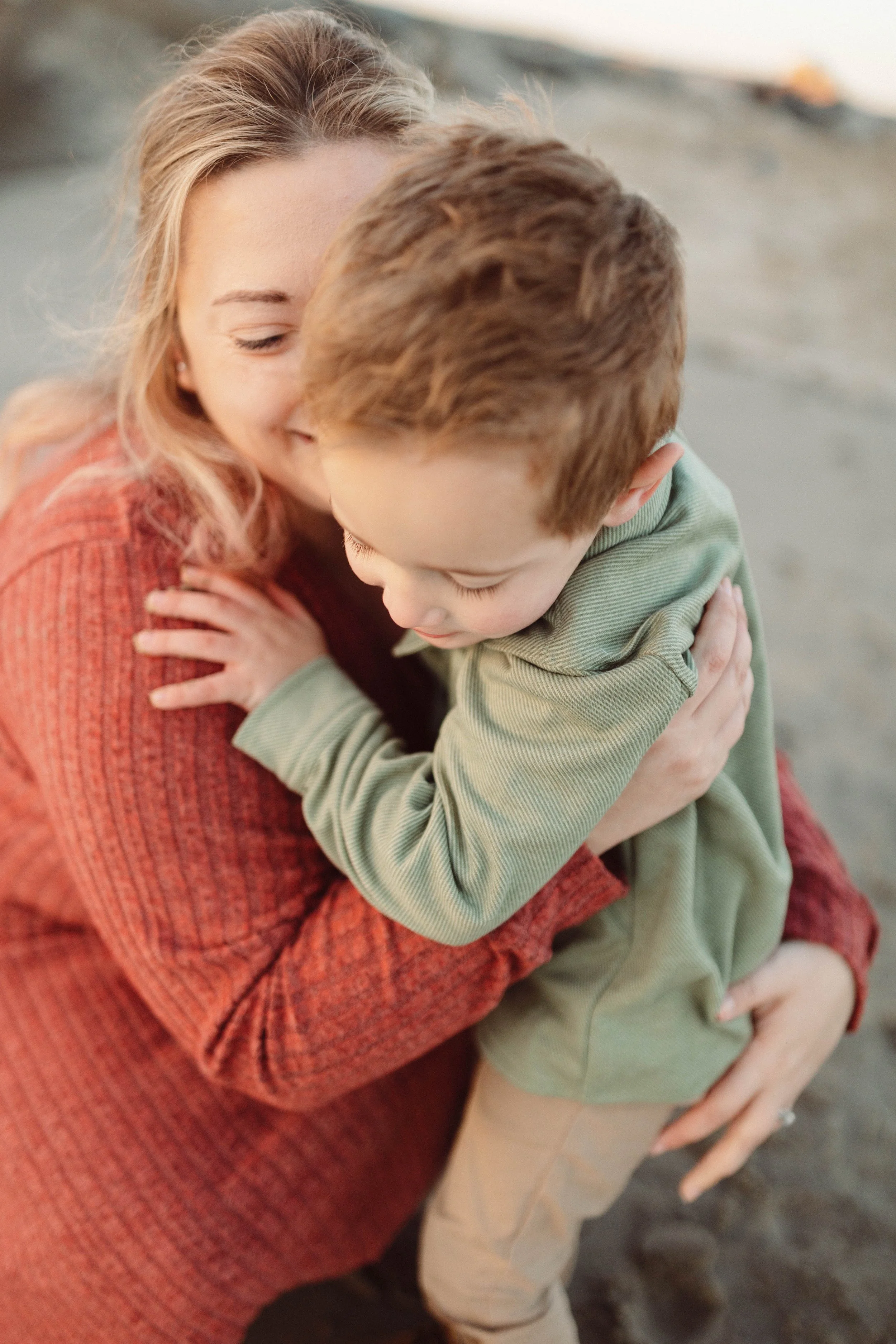 woman embracing son in an intimate playful moment on a beach
