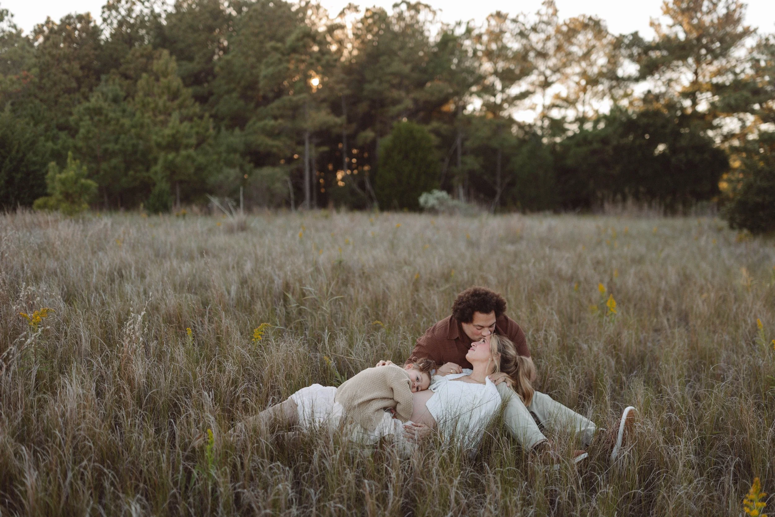 Virginia Beach family maternity portrait of couple and daughter relaxing in a field at Pleasure House Point