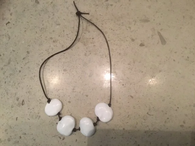 4 large white flat beads on brown leather.JPG