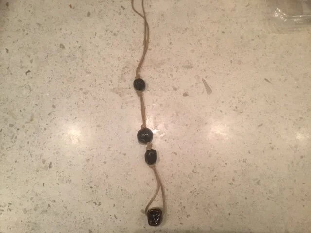 4 black beads ( 1 marshmallow) on tan suede.JPG