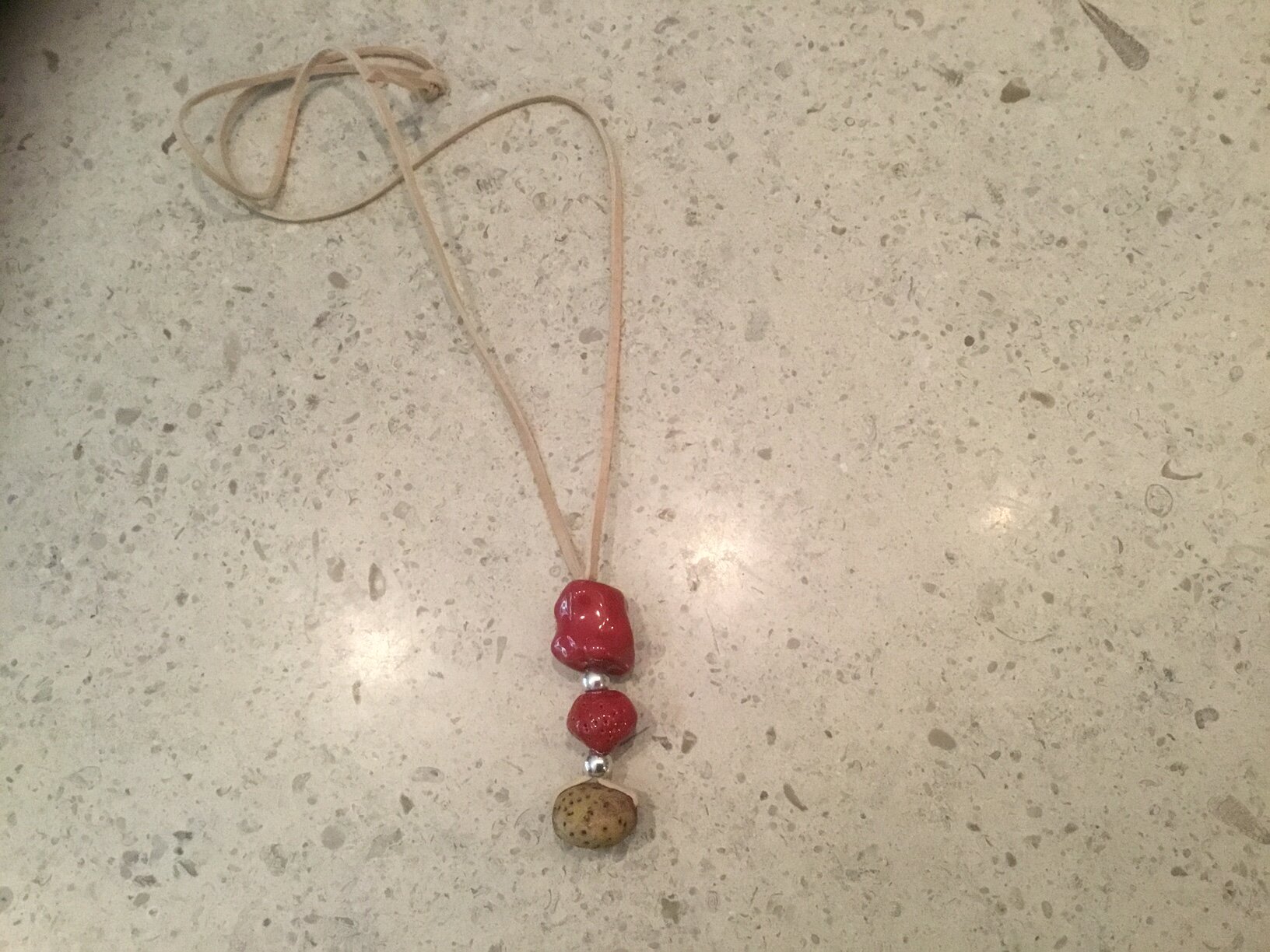 2red beads, 1 poked tan, silver fittings, on beige suede.JPG