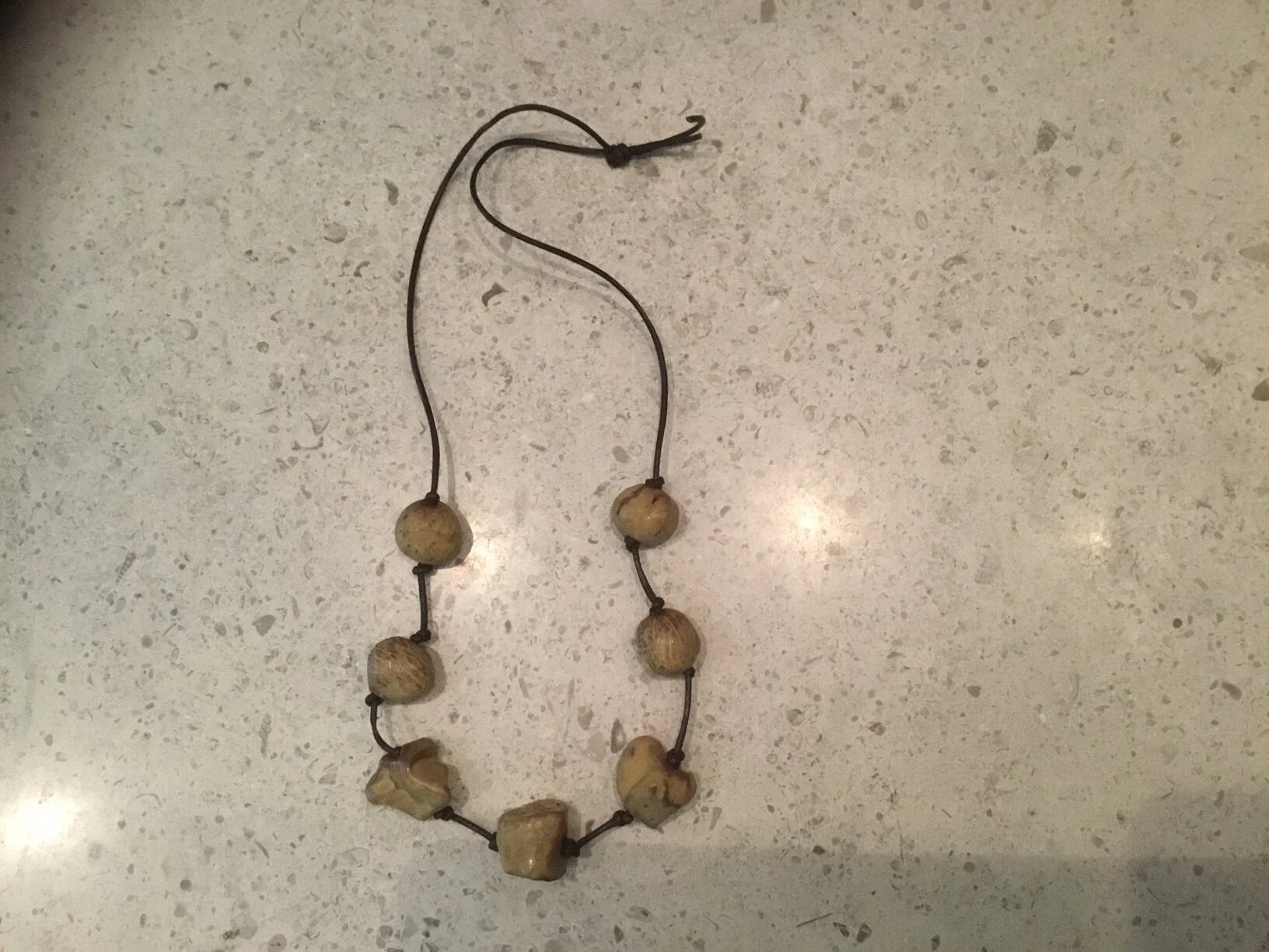 7 organic tan rock beads on brown leather.JPG