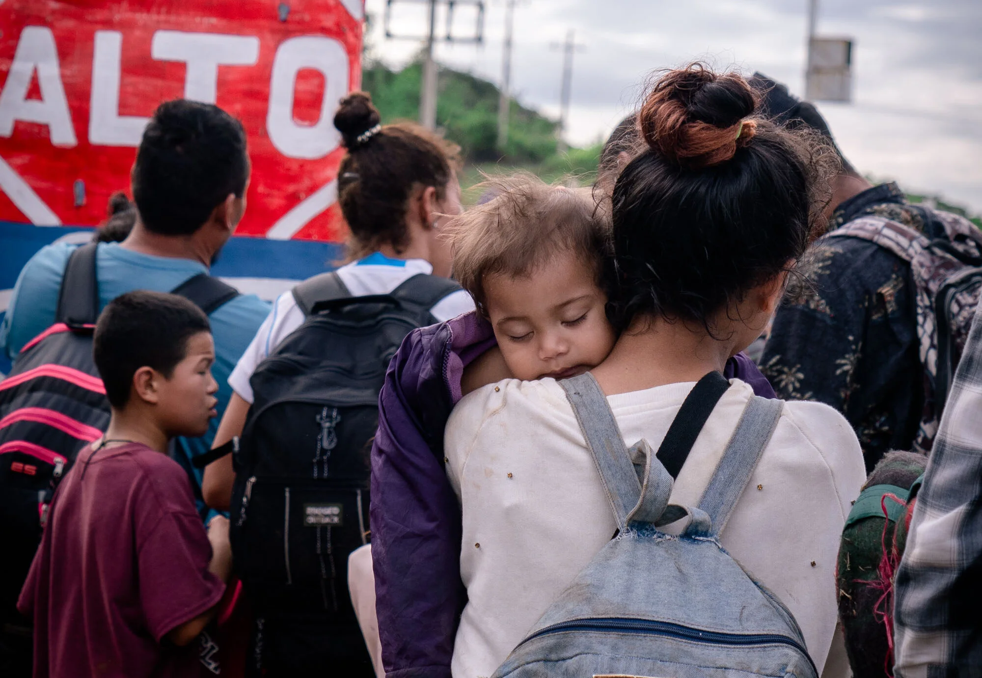  A mother and member of a migrant caravan carries her baby as they wait to cross the Guatemala - Mexico border.   January 2020 