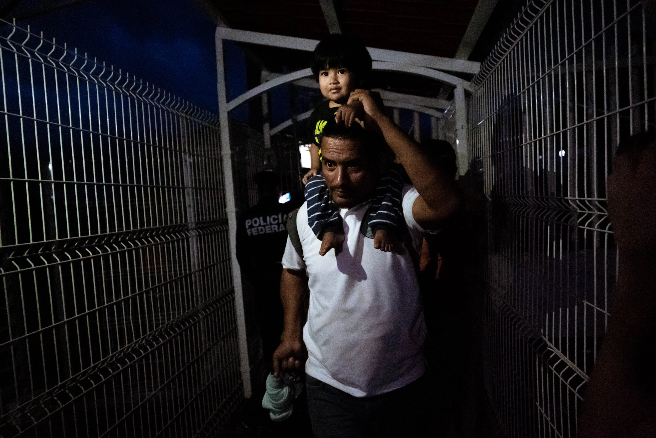  A father carries his child as he passes through the Mexico-Guatemala border on his journey northward.   January 2020 