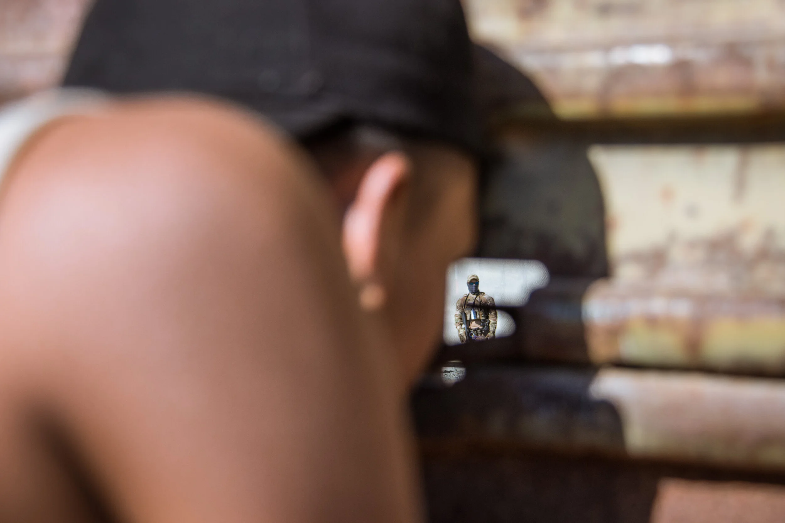  A young member of the migrant caravan peers through a hole in the border wall in Tijuana, Mexico, 2018. 