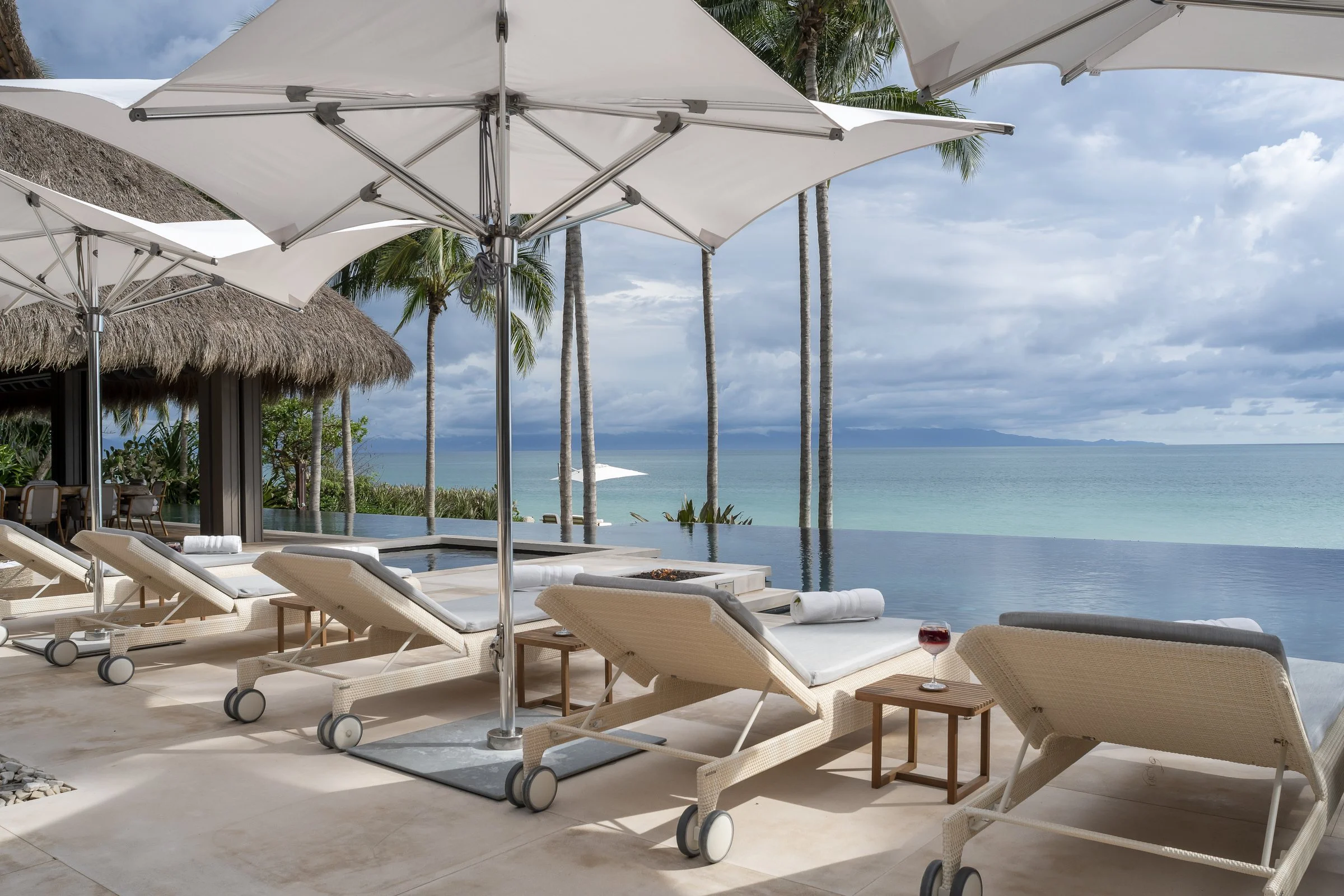 Loungers and umbrellas beside the infinity pool, ocean beyond