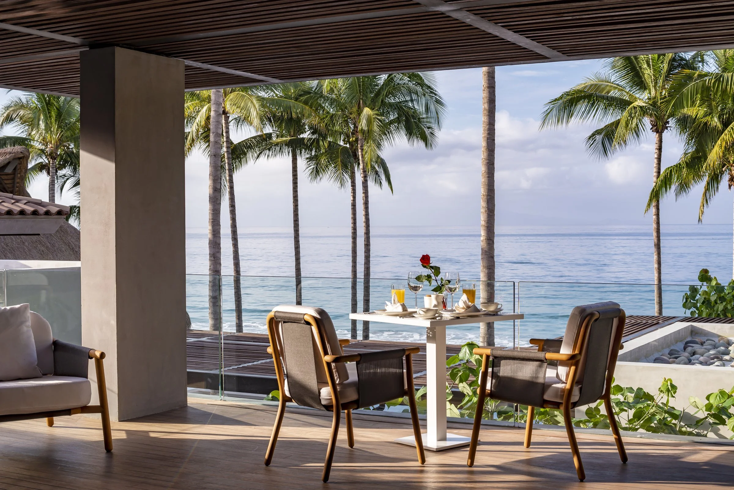 A covered terrace with breakfast table for two above the ocean