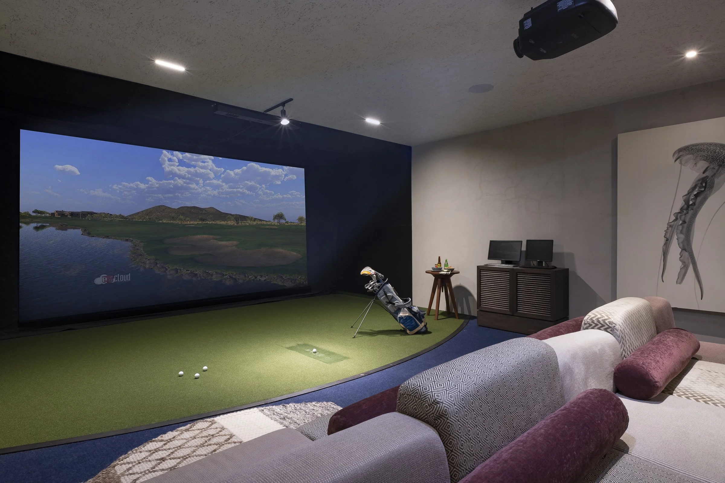 The golf simulator, screen lit with a course and clubs at the ready
