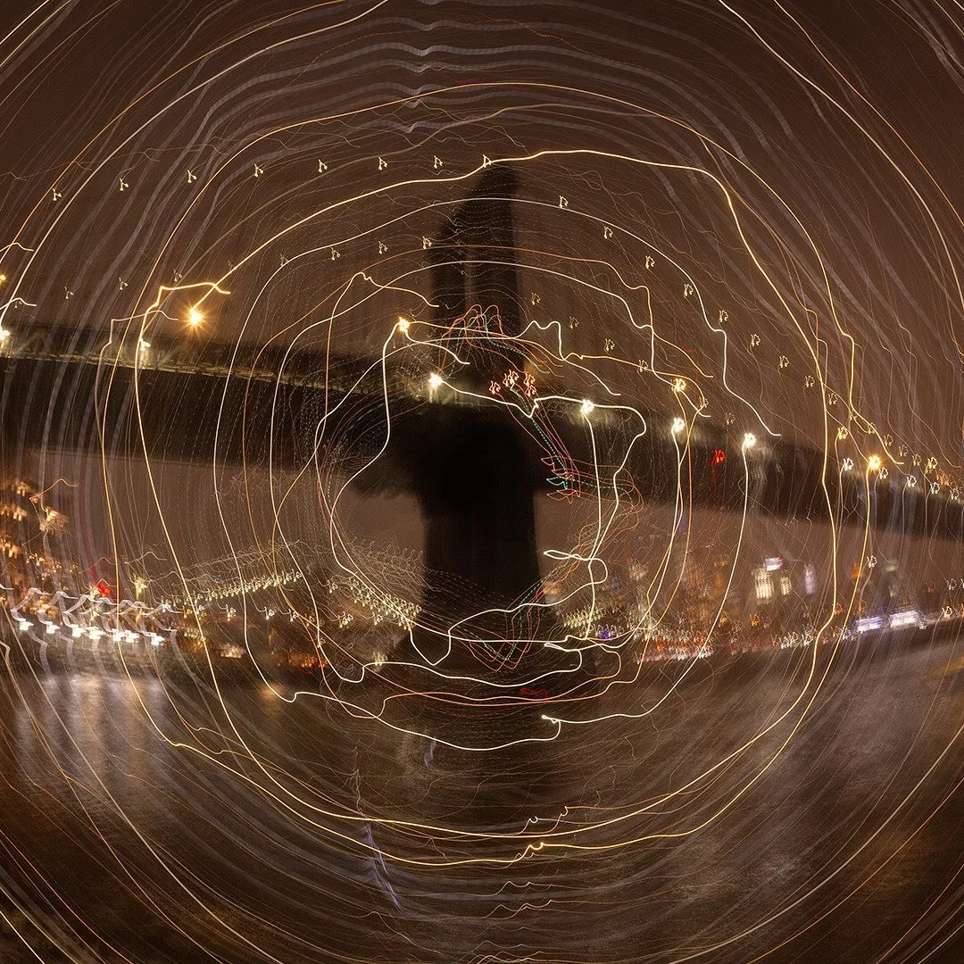 The Manhattan Bridge photographed with a long exposure on a fisheye lens. The photograph was taken from John Street Park, Brooklyn on Sunday, January 31st 2021 at 7:36PM at the start of a snow storm. During the handheld 5 second exposure I rotated th