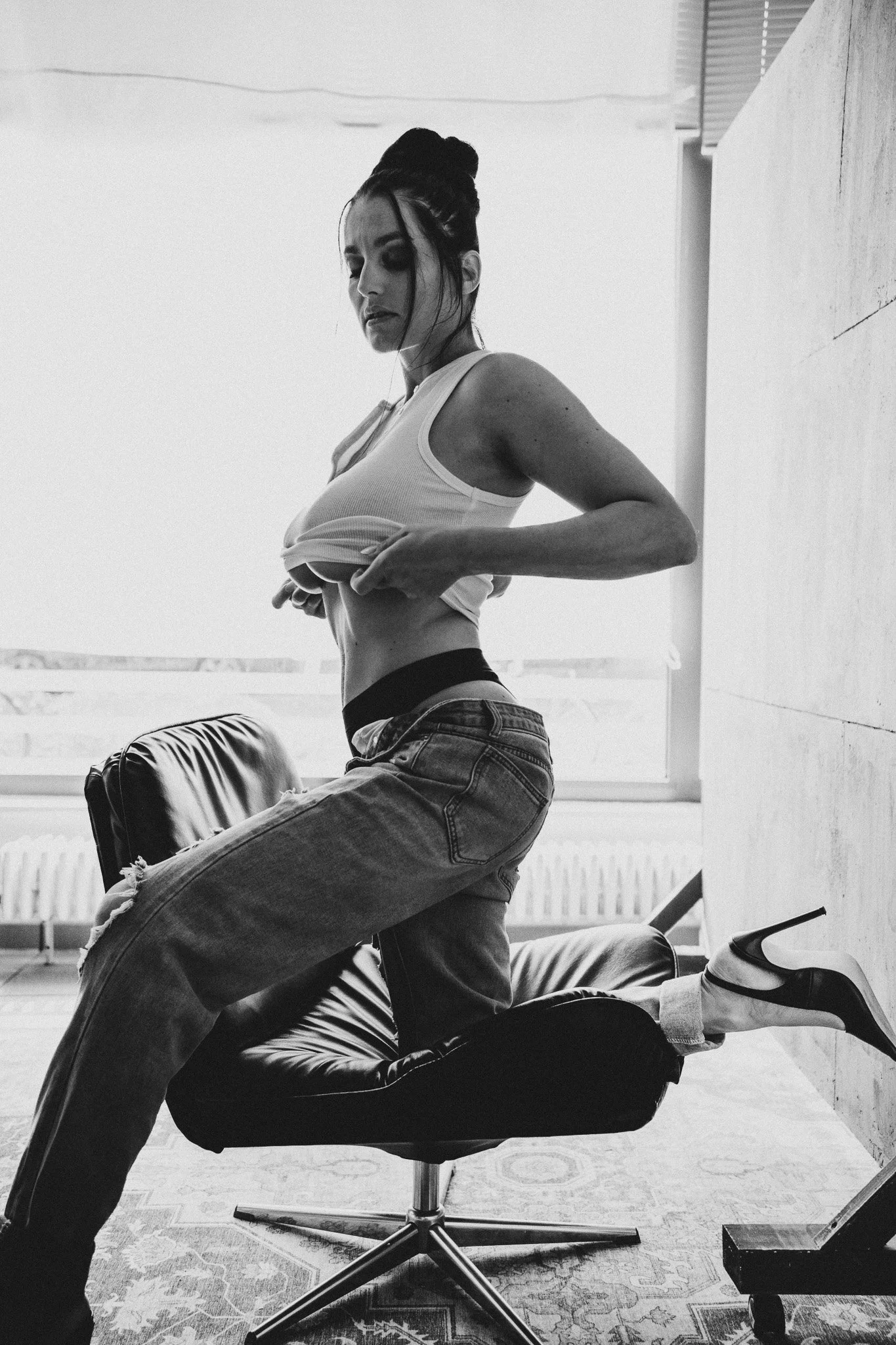 Drei Frauen in einem Raum, die eine Yoga- oder Stretching-Übung auf einem Stuhl machen, in schwarz-weiß.