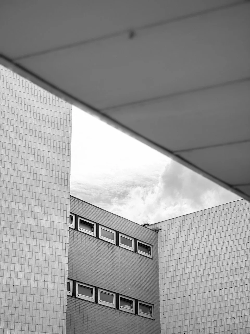 Schwarze und weiße Aufnahme von Gebäuden mit rechteckigen Fenstern und einer gebänderten Außenfassade.