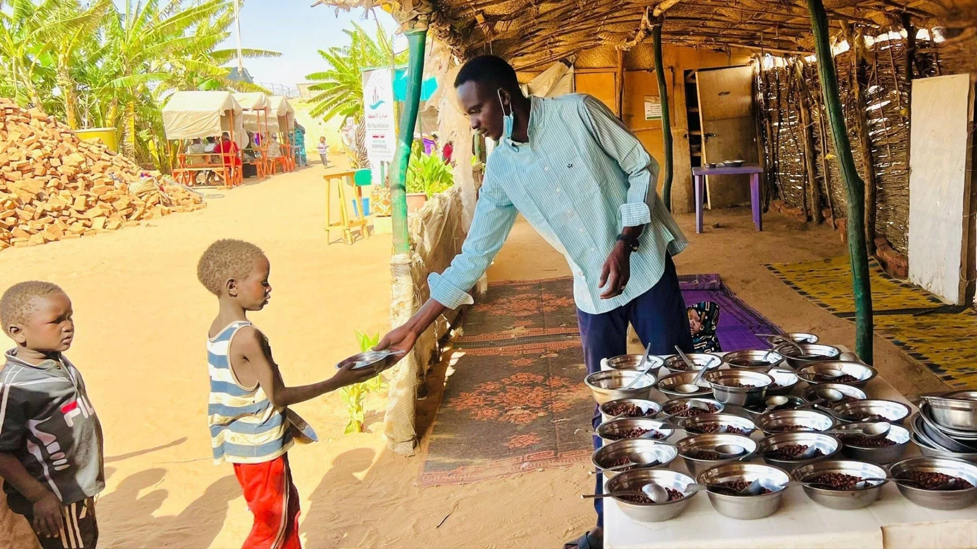 A healthcare worker feeds refugee children