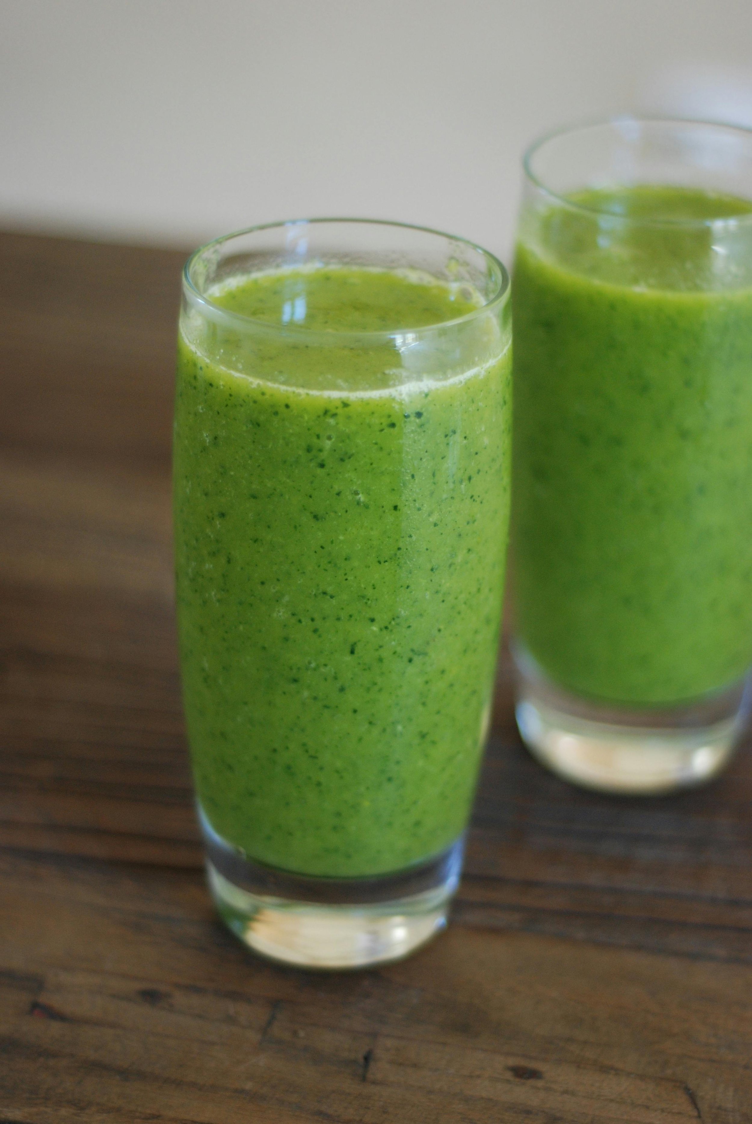 A nutritious green smoothie with fresh spinach and chia seeds sitting on a kitchen counter.