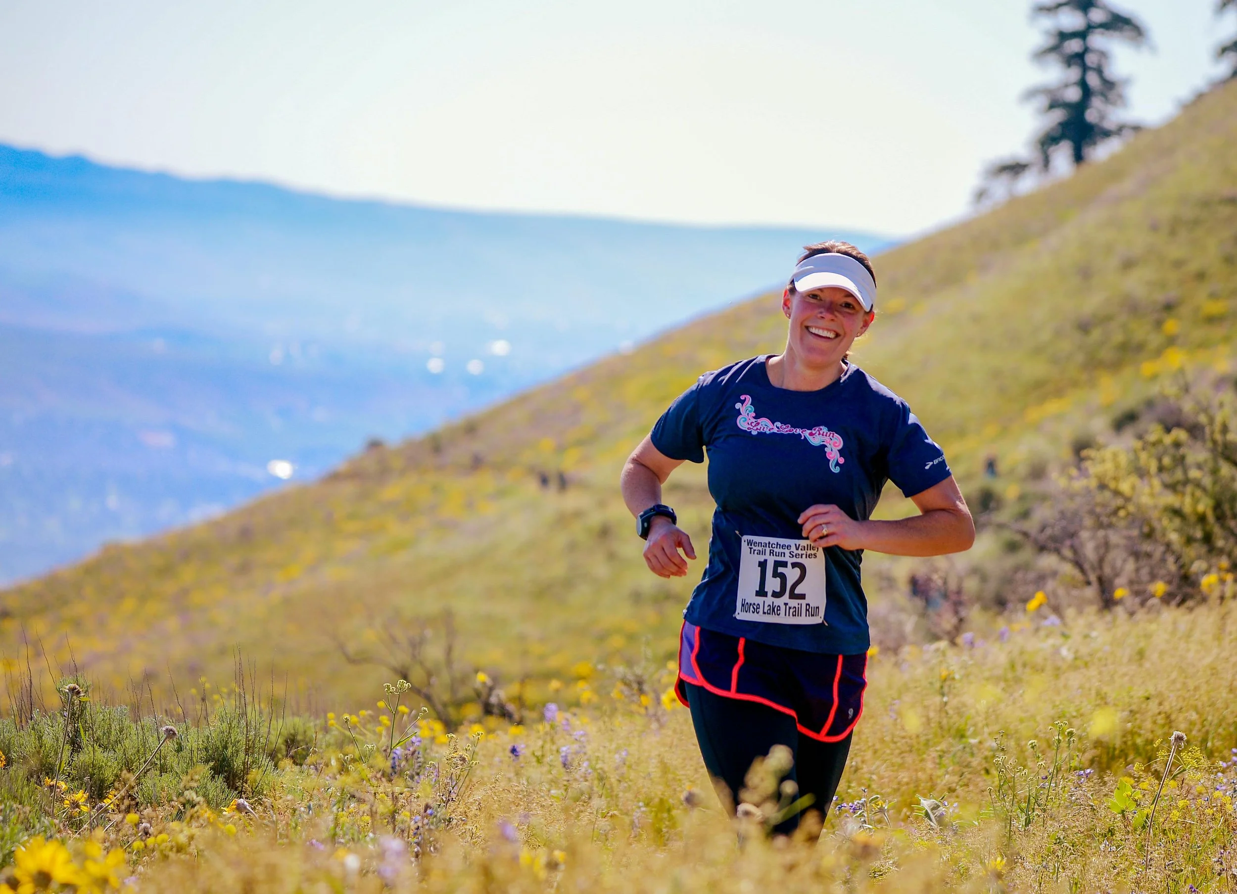 A woman trail running solo through a vibrant green forest, focusing on endurance and mental clarity.