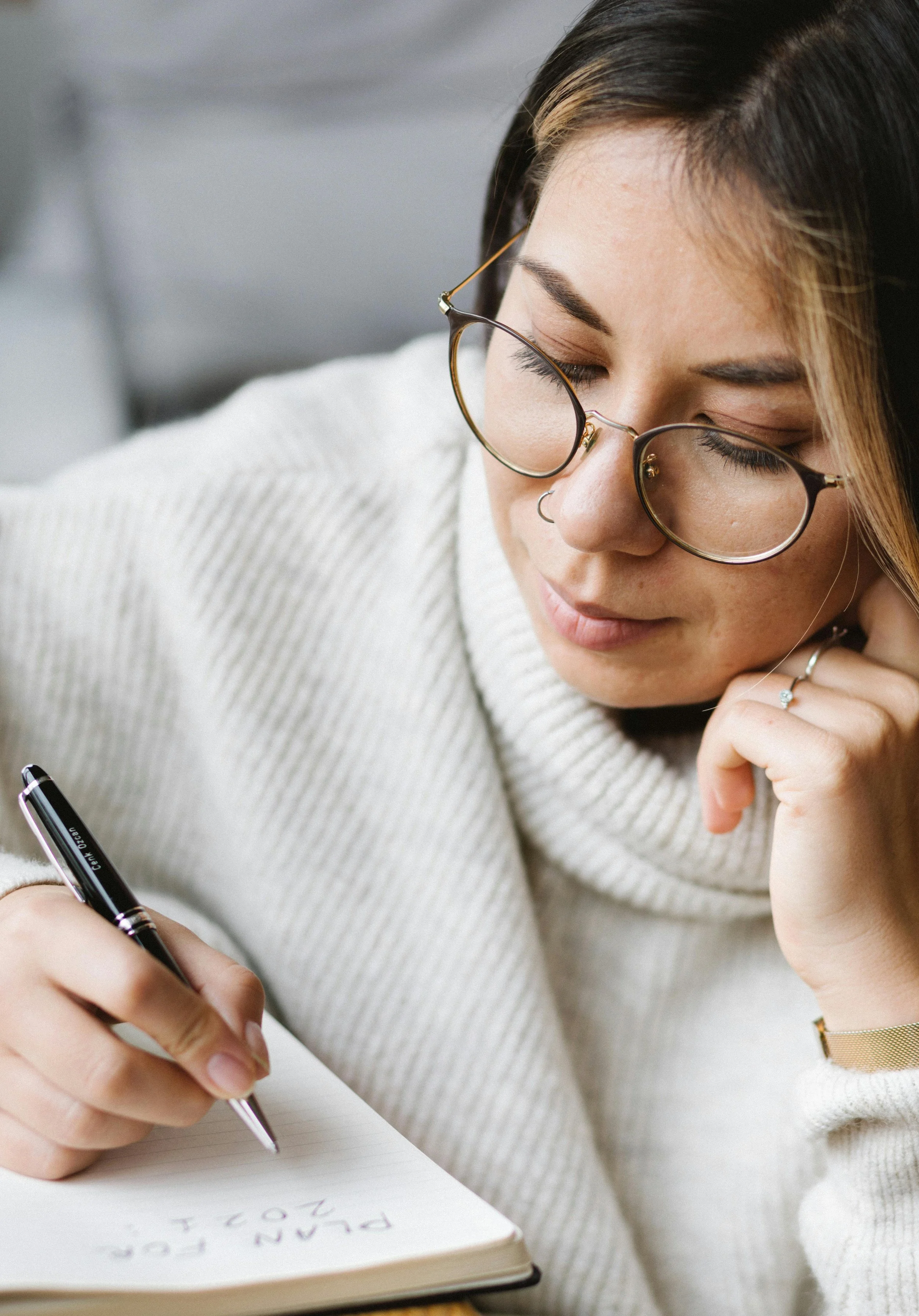 A woman with her eyes closed, deep in thought and taking notes.