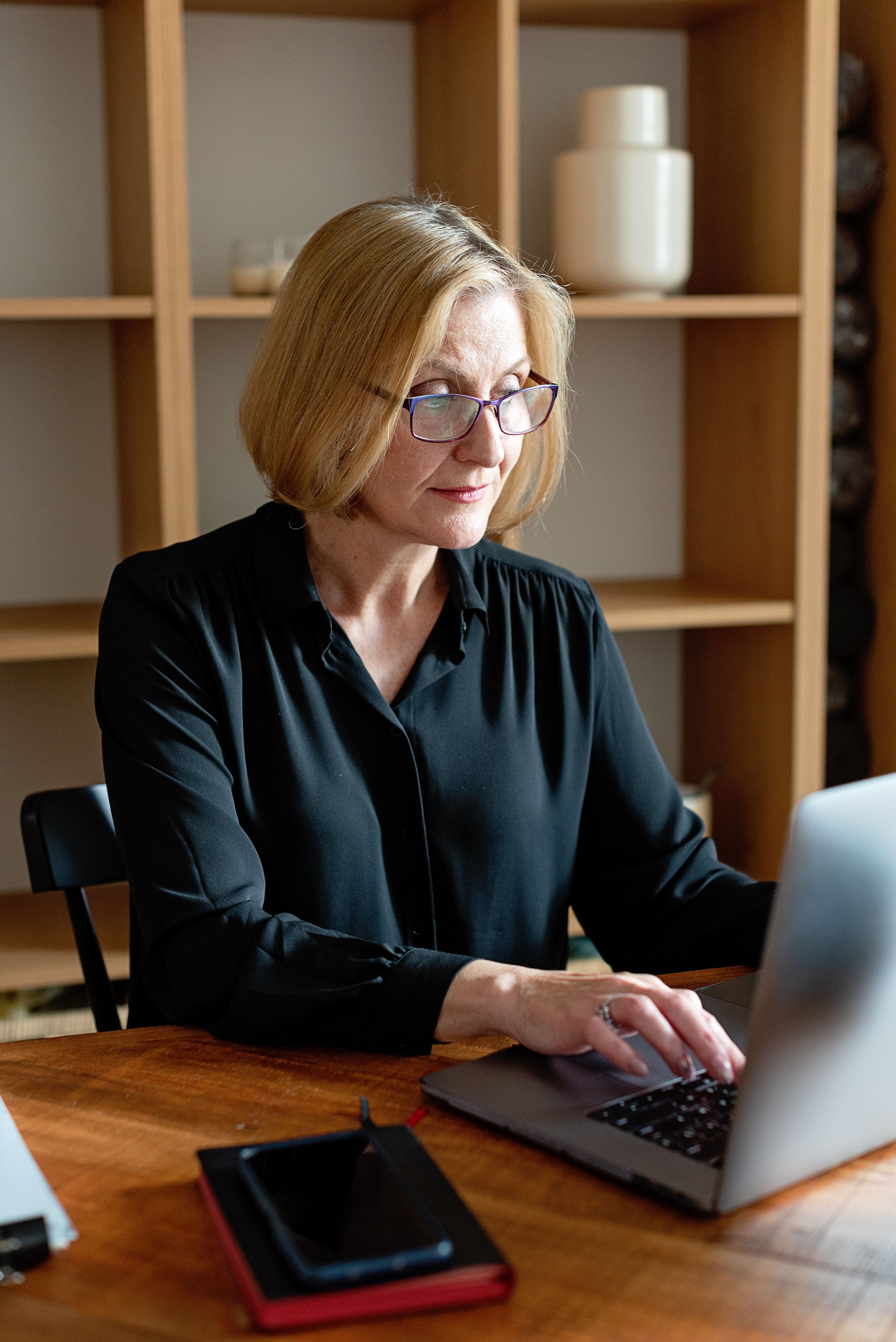 A focused menopausal woman working efficiently and happily at her laptop, representing clear cognitive health.