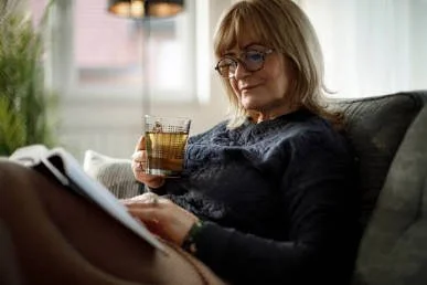 A relaxed and smiling woman enjoying tea, embracing the stress relief required for holistic menopause management.