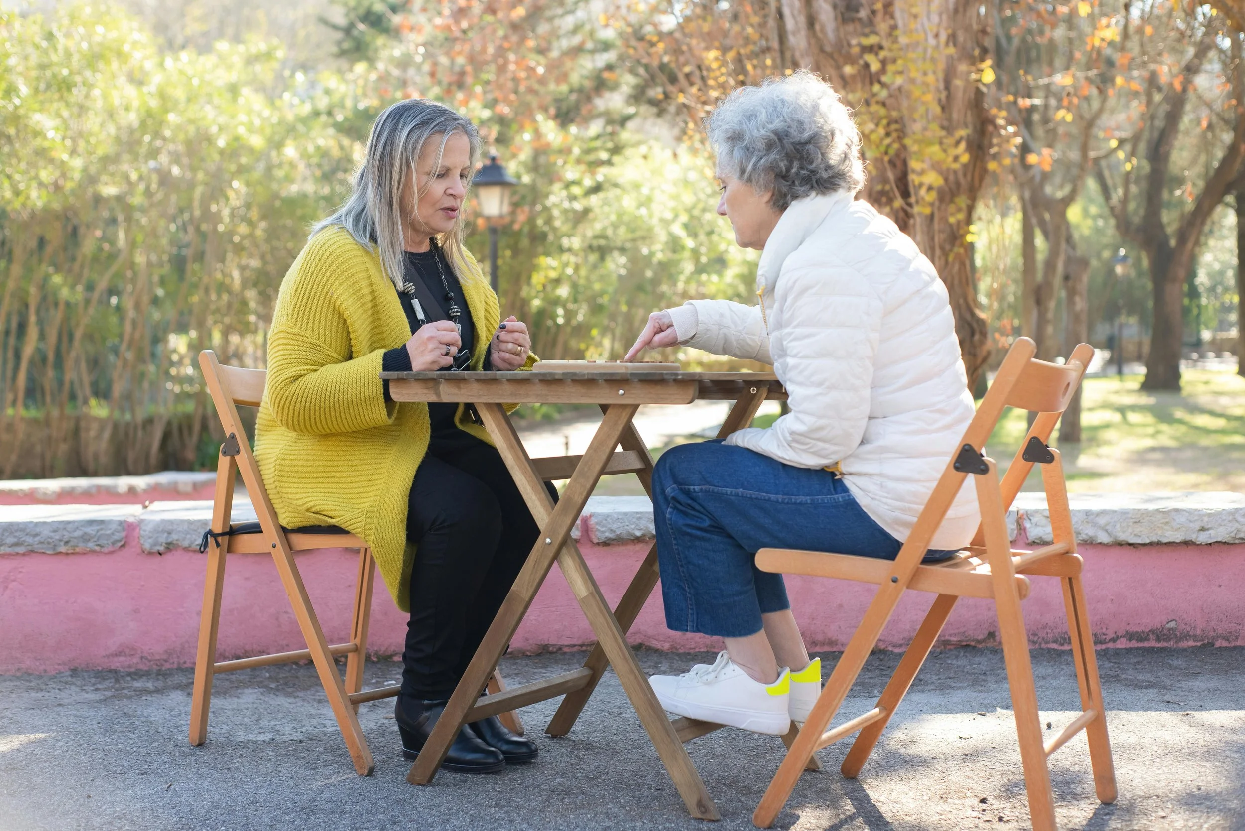 Group of midlife women playing Mahjong together at a table, laughing and socializing while engaging in a brain-stimulating game