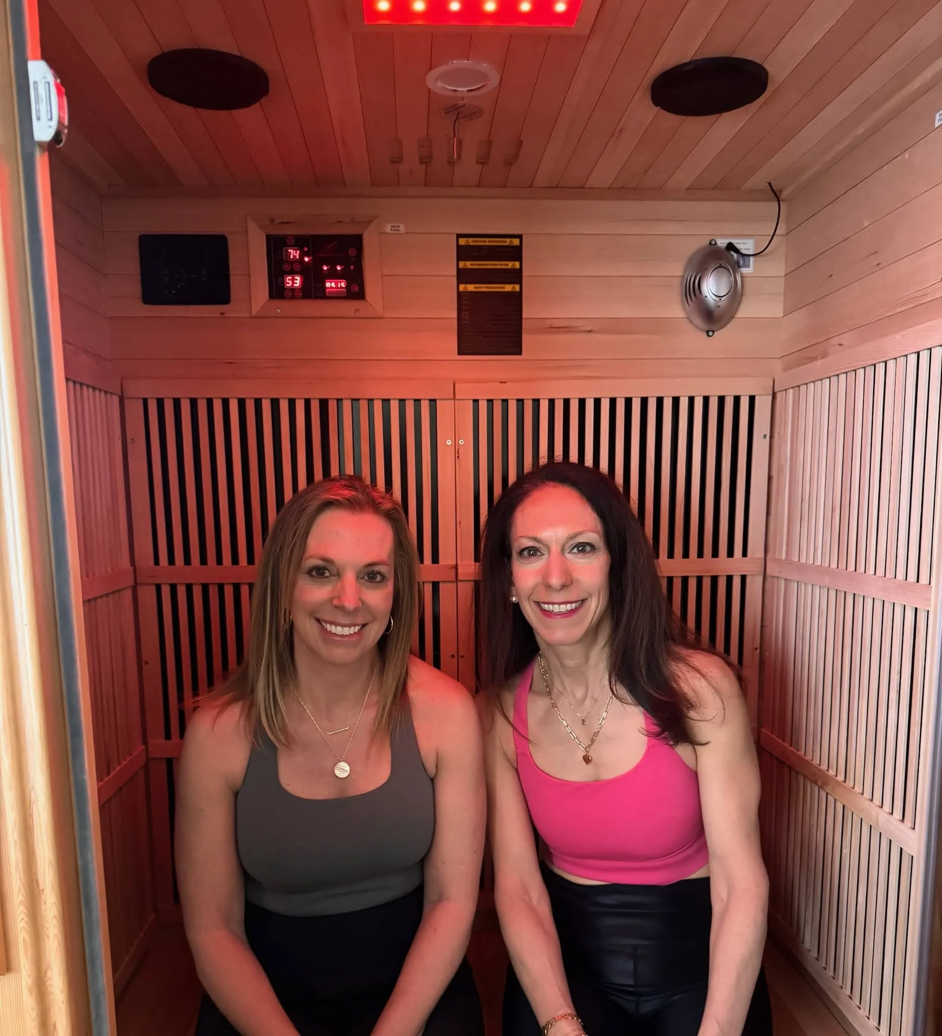A relaxed midlife woman sitting inside a wooden home sauna, experiencing infrared sauna benefits for stress relief and mental clarity.