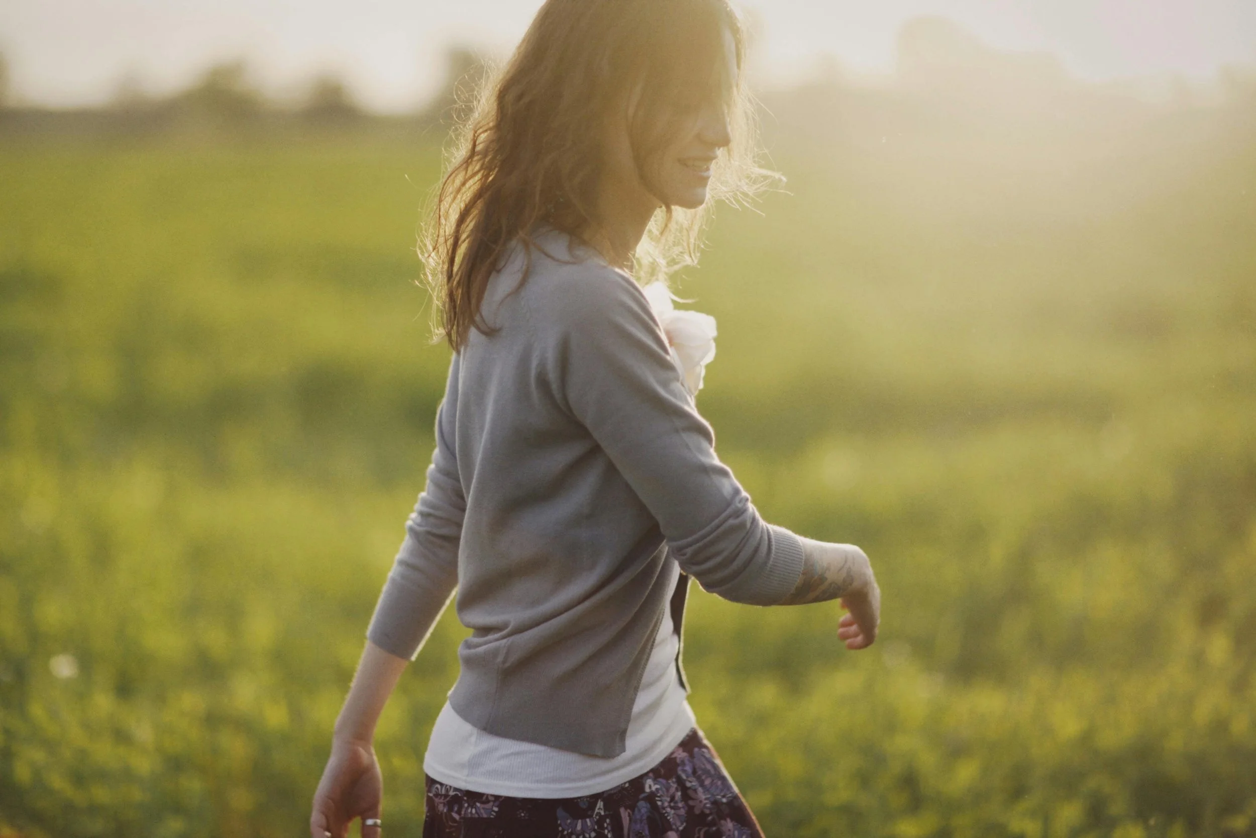 A vibrant midlife woman smiling and enjoying a walk in the morning sunlight to support her cellular health.