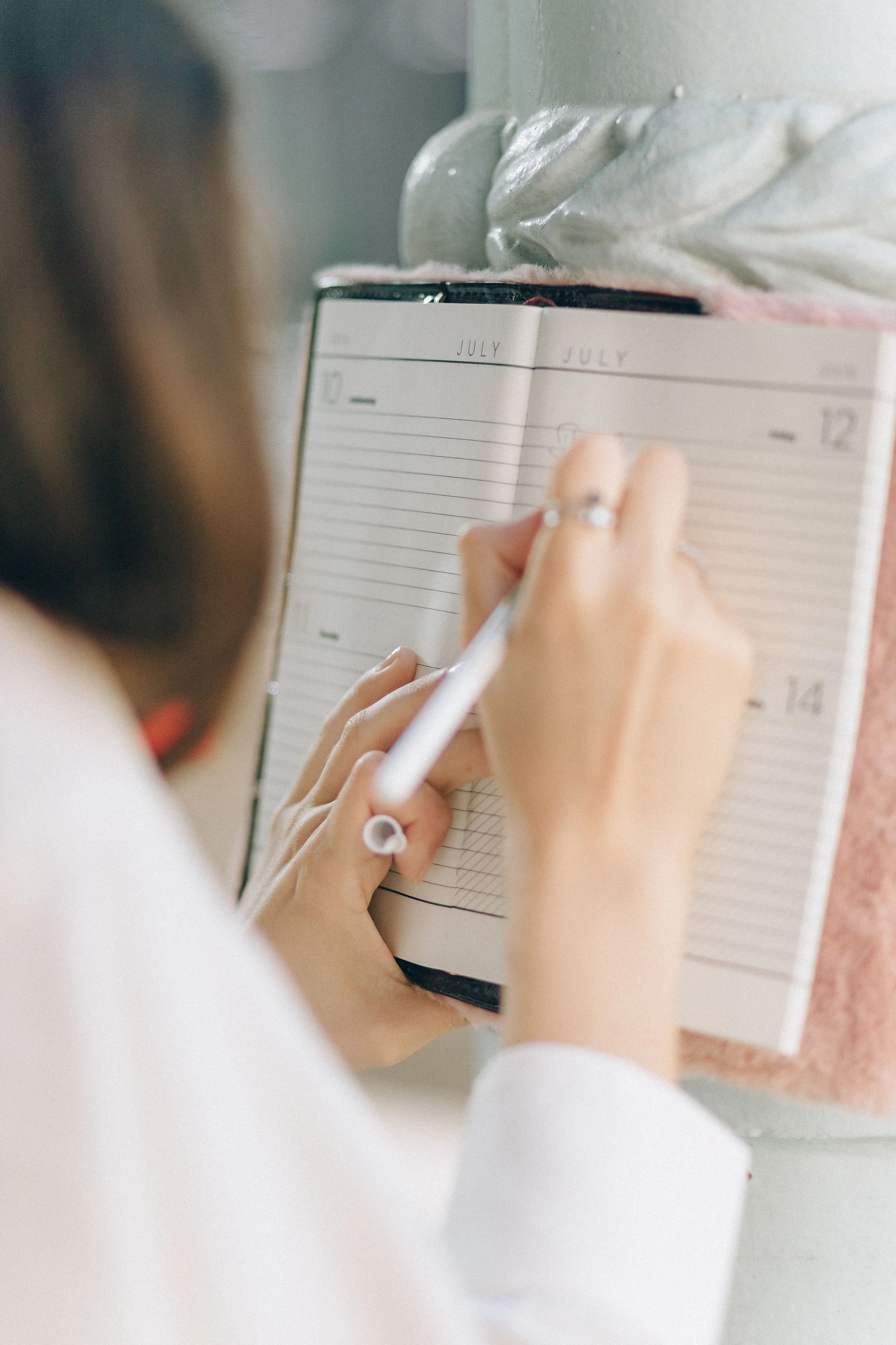 A woman writing in a daily wellness notebook to track her energy levels and physical responses during perimenopause.