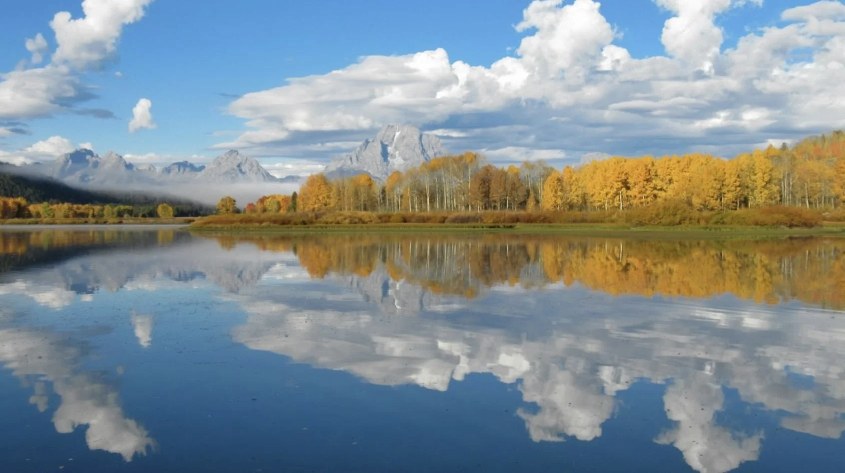Water and fall trees with mountains in the distance