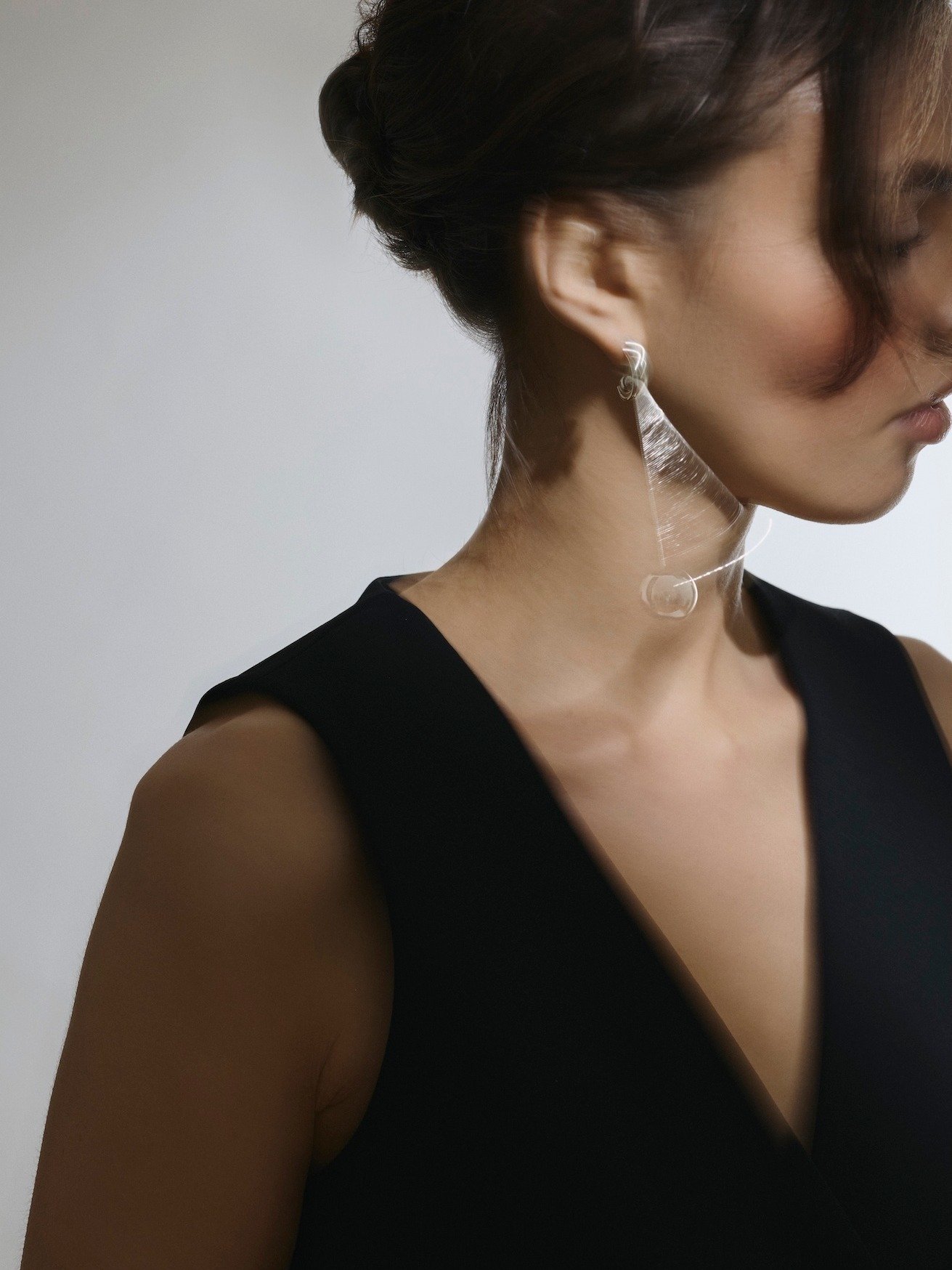 When everything else is quiet, the details become the story.

This image is built around one clear message: modern minimalism with a sculptural twist. The clean black neckline, the soft side profile and the almost weightless earring create a visual l