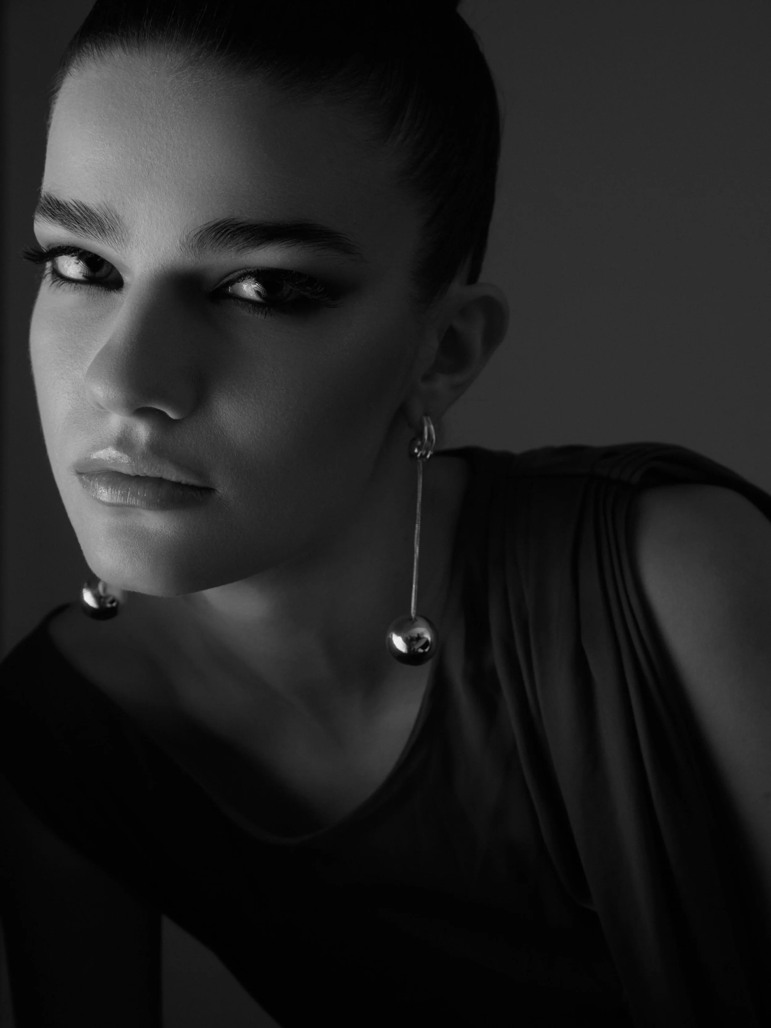 Light and shadow as a creative decision.

When the frame does most of the talking, styling becomes architecture &mdash; each element placed with intention, nothing left to chance. The earring catches the light. The rest recedes. That contrast is the 