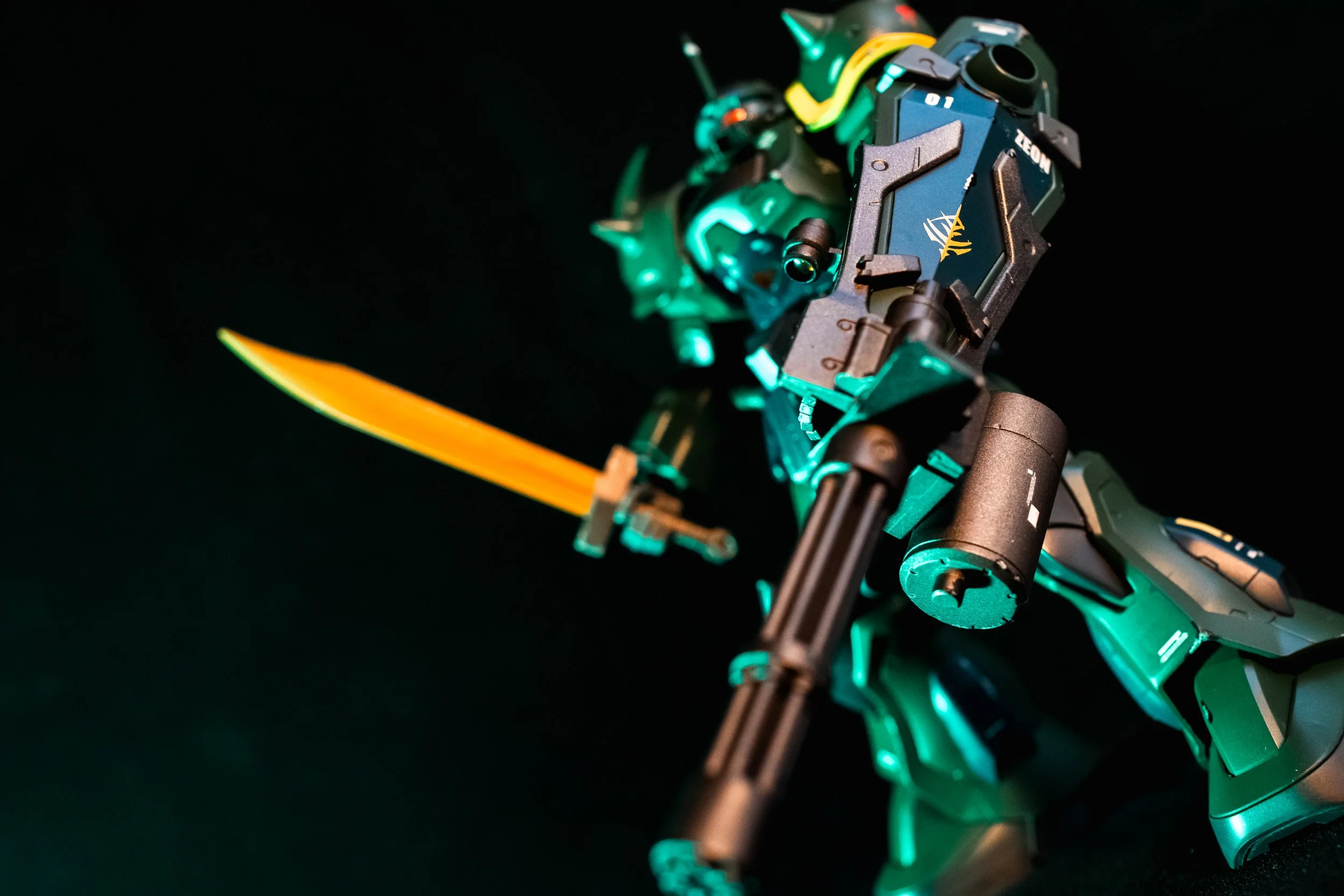 A detailed toy figure of a robot warrior holding a yellow sword, with a futuristic design and glowing accents, set against a black background.