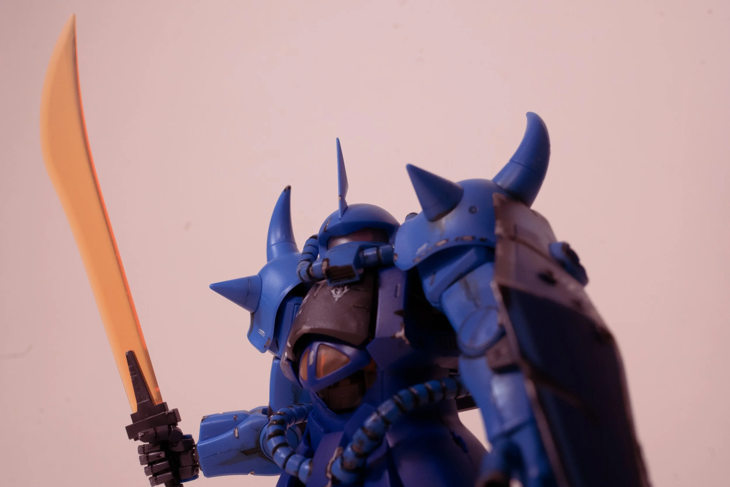 A blue armored robot with horns, holding a sword, against a plain background.