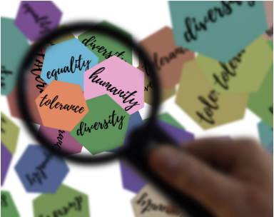 Hand holding magnifying glass focusing on stickers of equality, humanity, tolerance and diversity