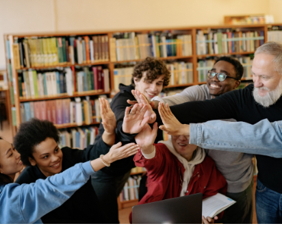 Neutral Male teacher and group of happy young students  with hands raised in a circle for unity