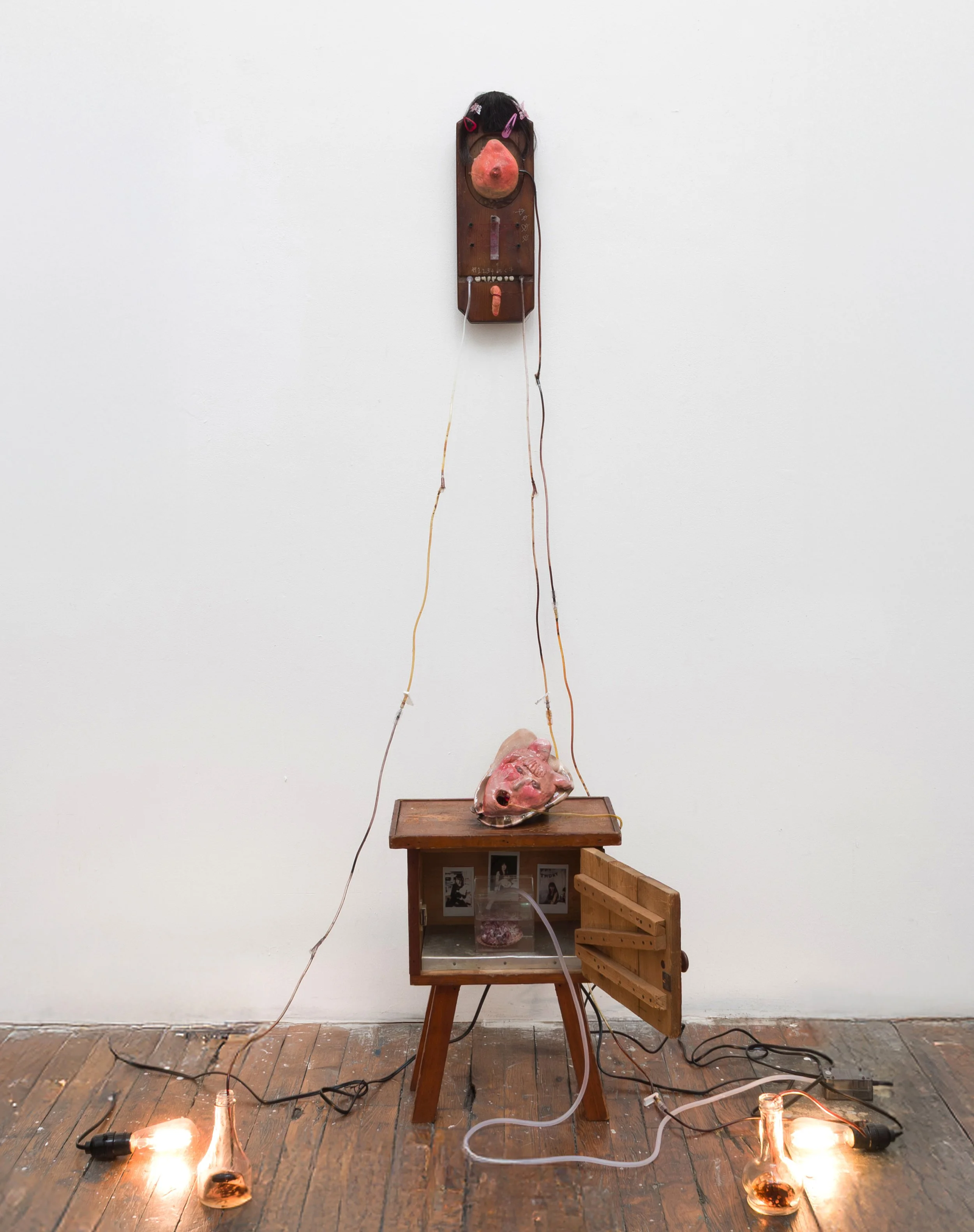    Dreaming by a Thread  , 2025 Nightstand, wall mirror, wooden box, seashell, stone clay, air pump, IV line,  oil, lamp, butterfly specimen, glass bottle, epoxy, synthetic hair, paraffin wax, and Polaroid photograph Approximately 80 × 30 × 30 inches