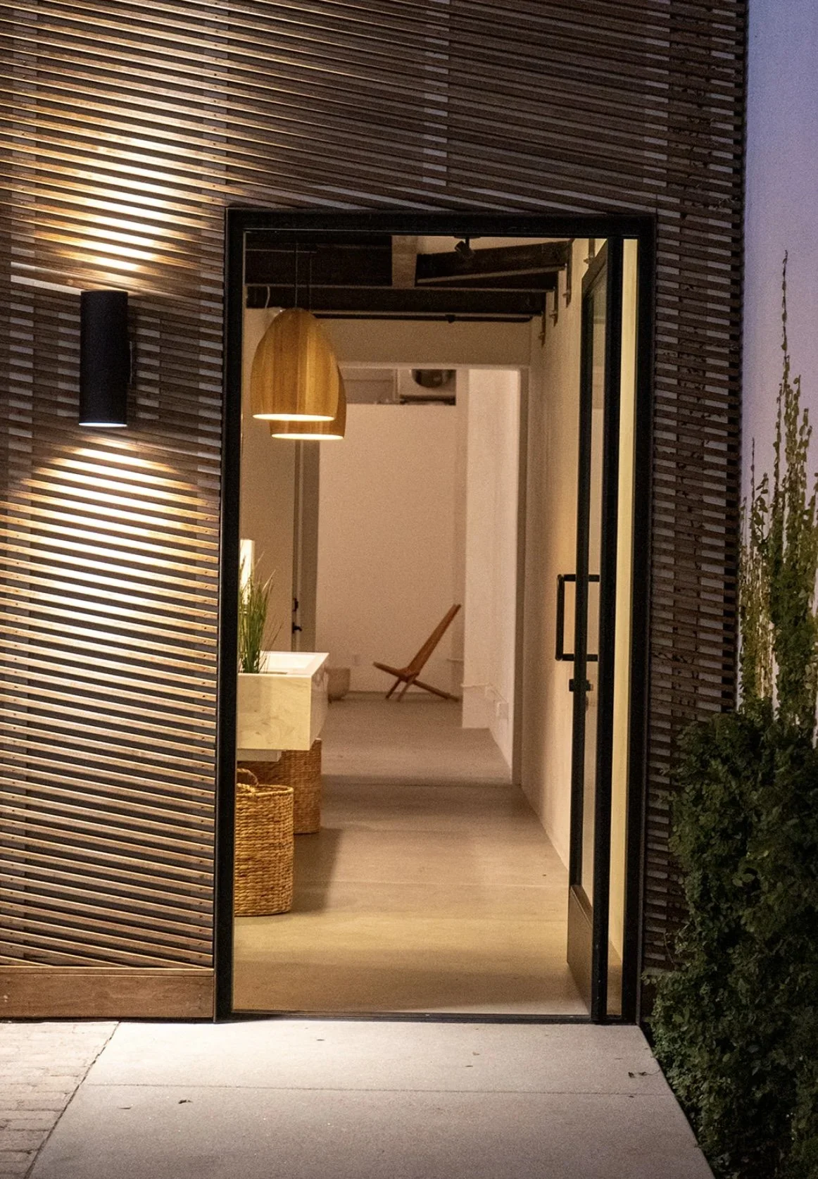 Lacuna restroom building entry at night with Kebony wood slats and Ross Gardam pendant light West Adams Los Angeles