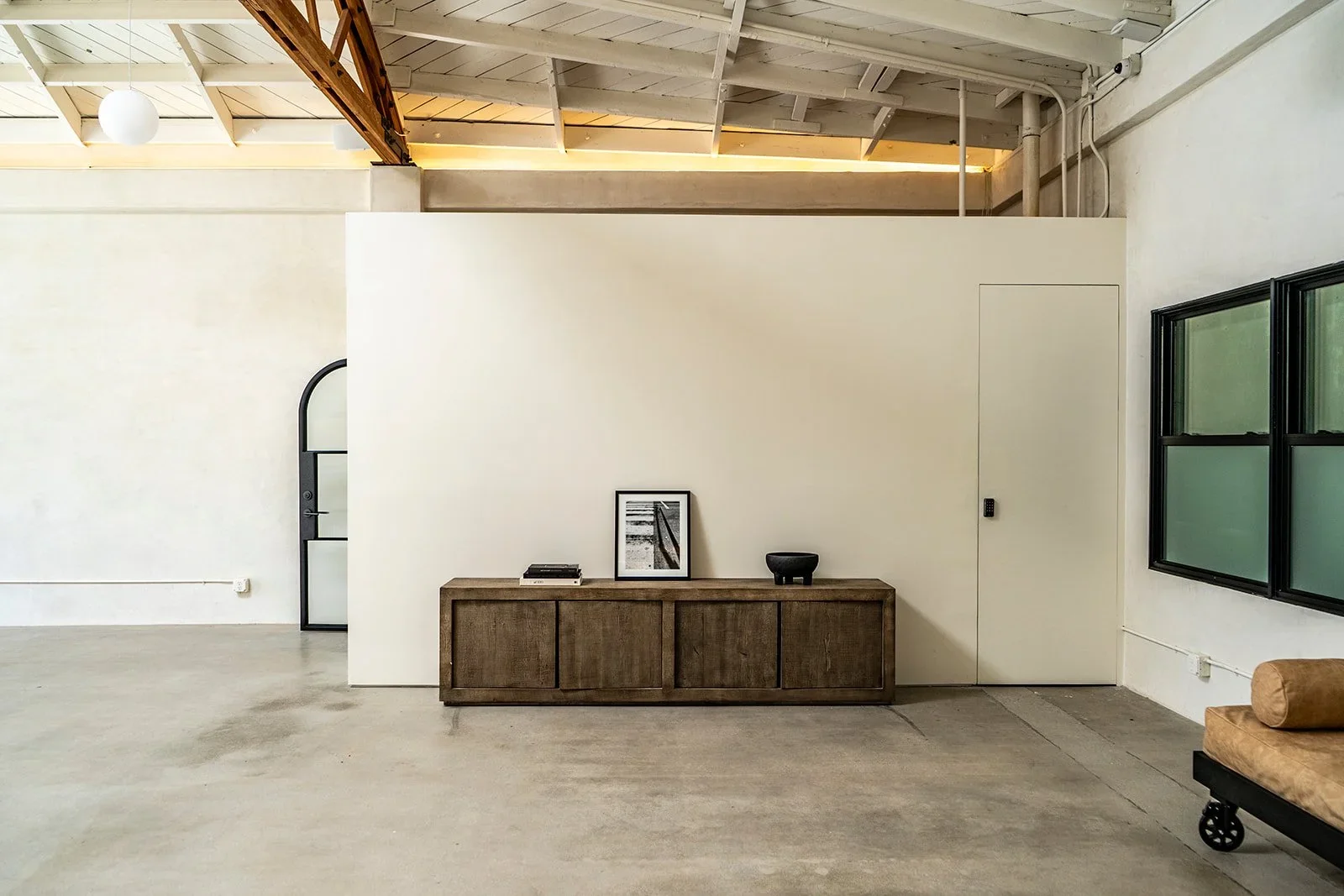 Lacuna event space interior with wood credenza polished concrete floors and bow truss ceiling in West Adams Los Angeles