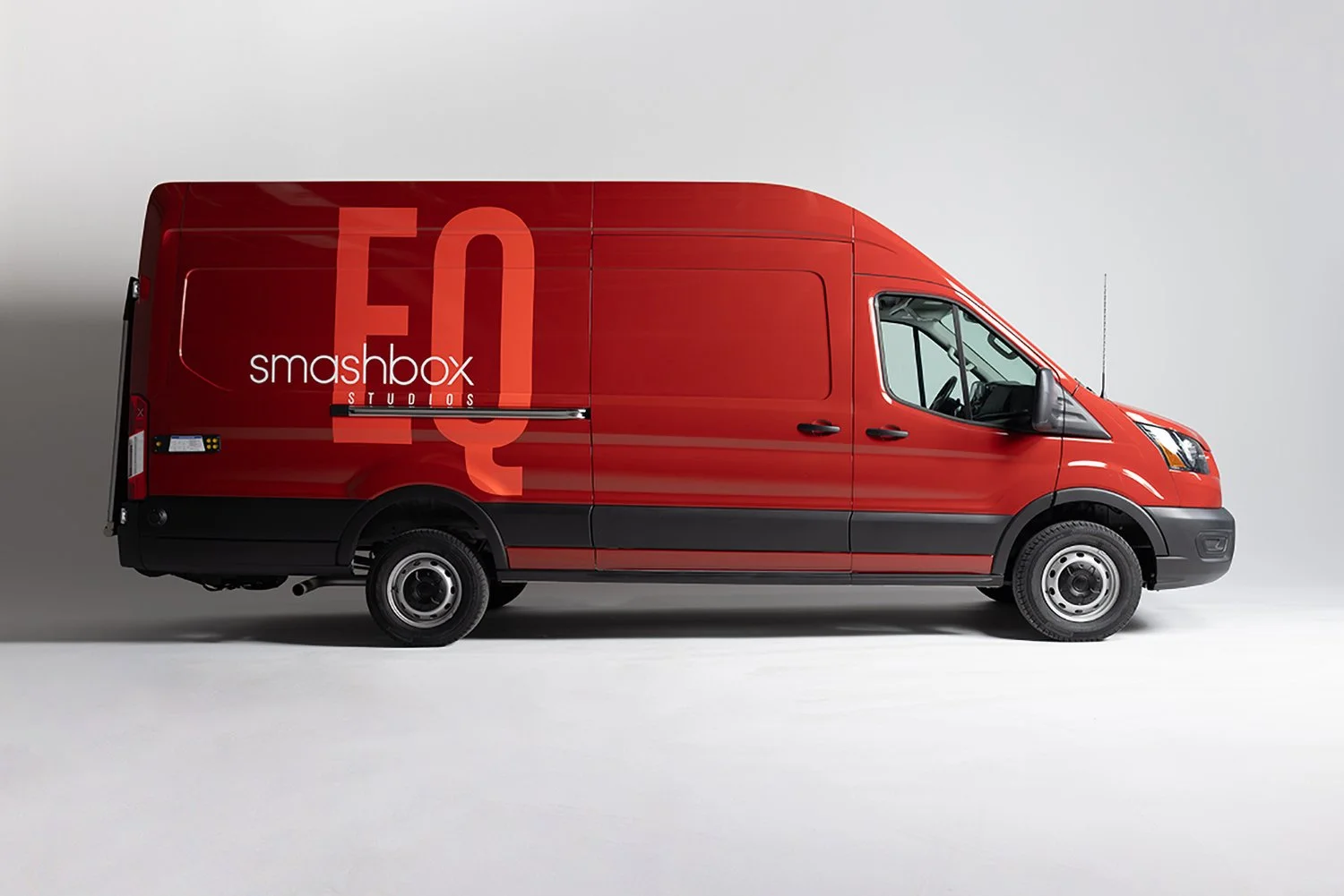 Red delivery van with Smashbox Studios branding on the side, parked on a plain grey background.