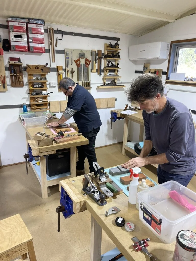 Two participants sharpening plane irons at the bench at a workshop at Moonlite Studios, Mount Egerton