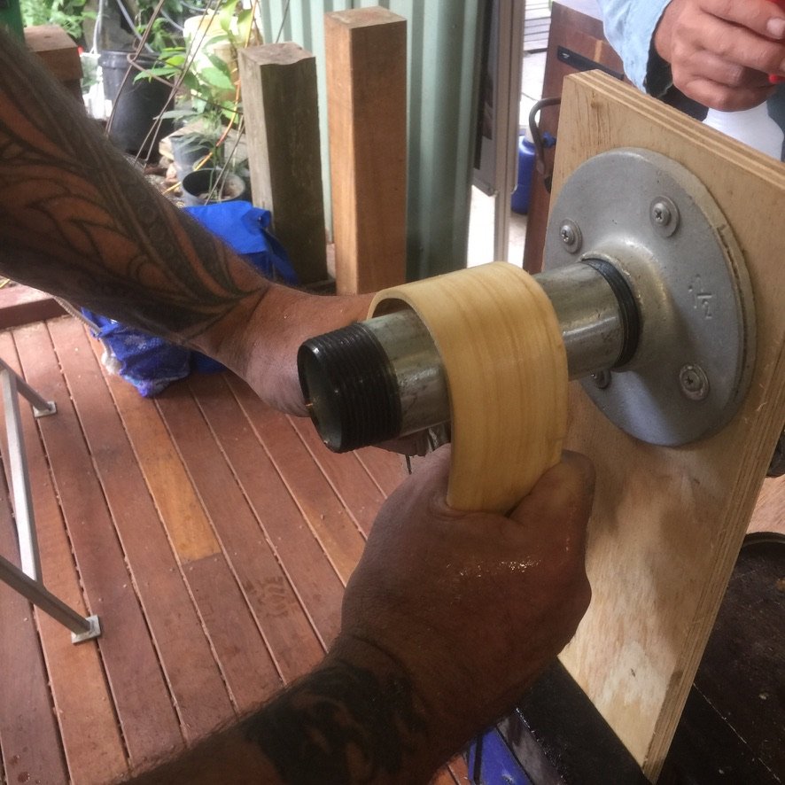 Hands bending a silver ash strip on a hot pipe in Ross Annels' studio at Black Mountain