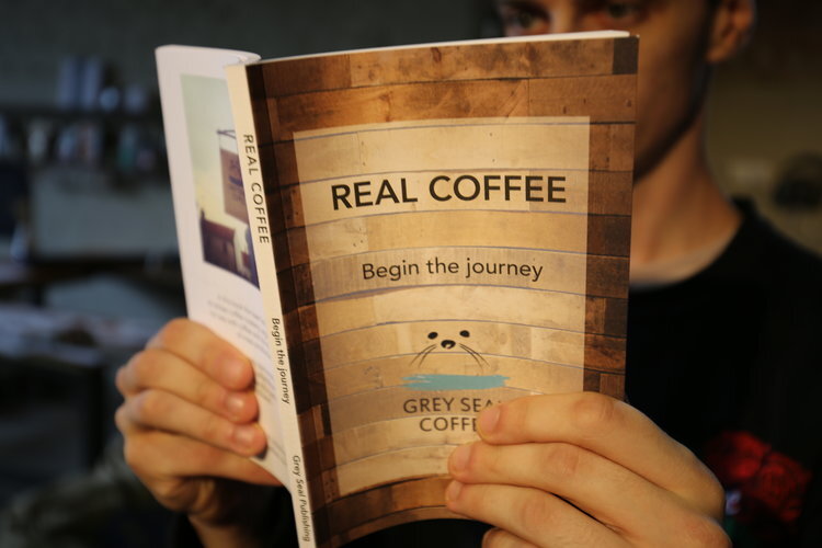 Grey Seal Real Coffee book being held in hands and read