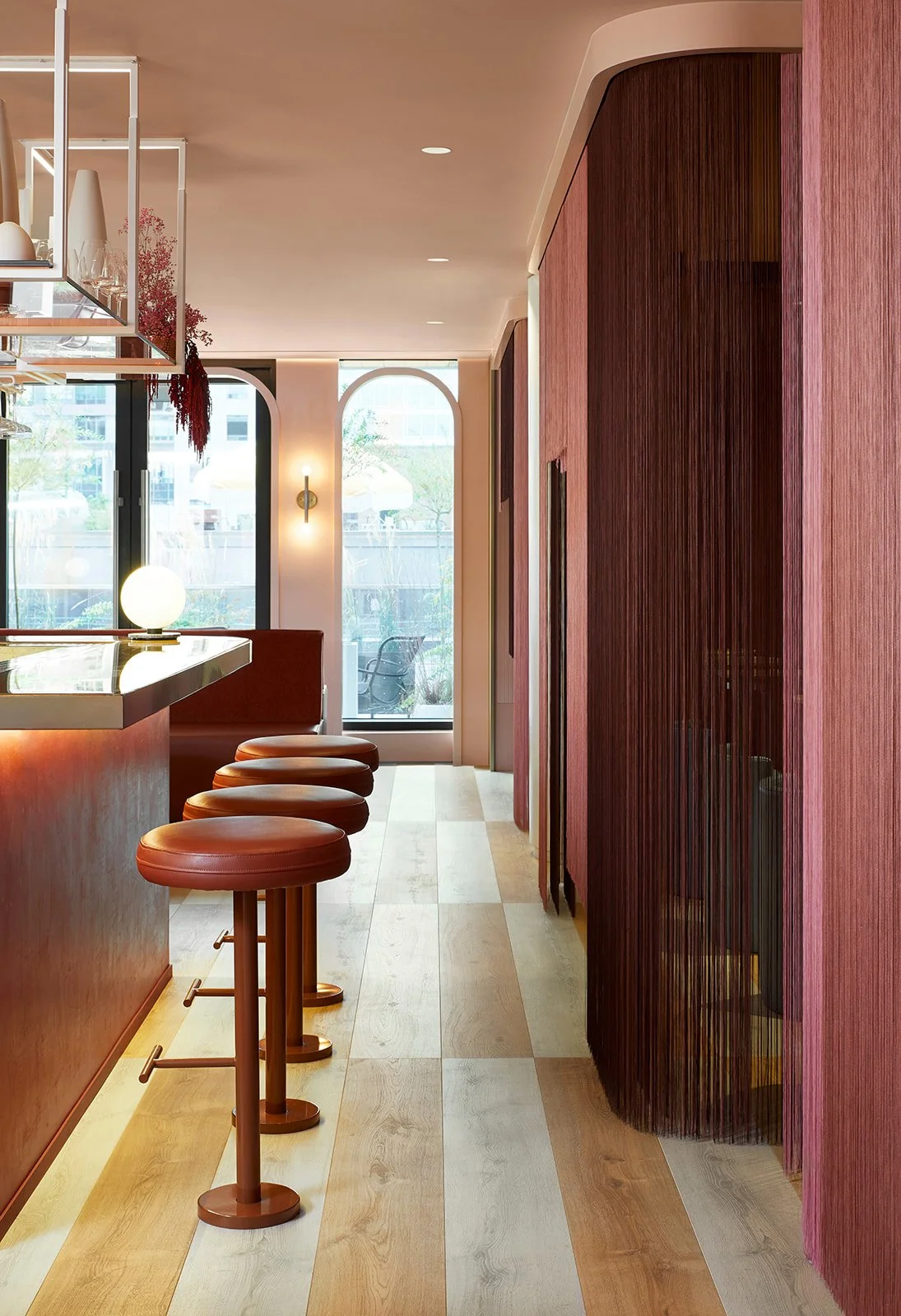 Interior of a modern café or bar with a marble countertop, four brown barstools, large windows, and wooden accents.