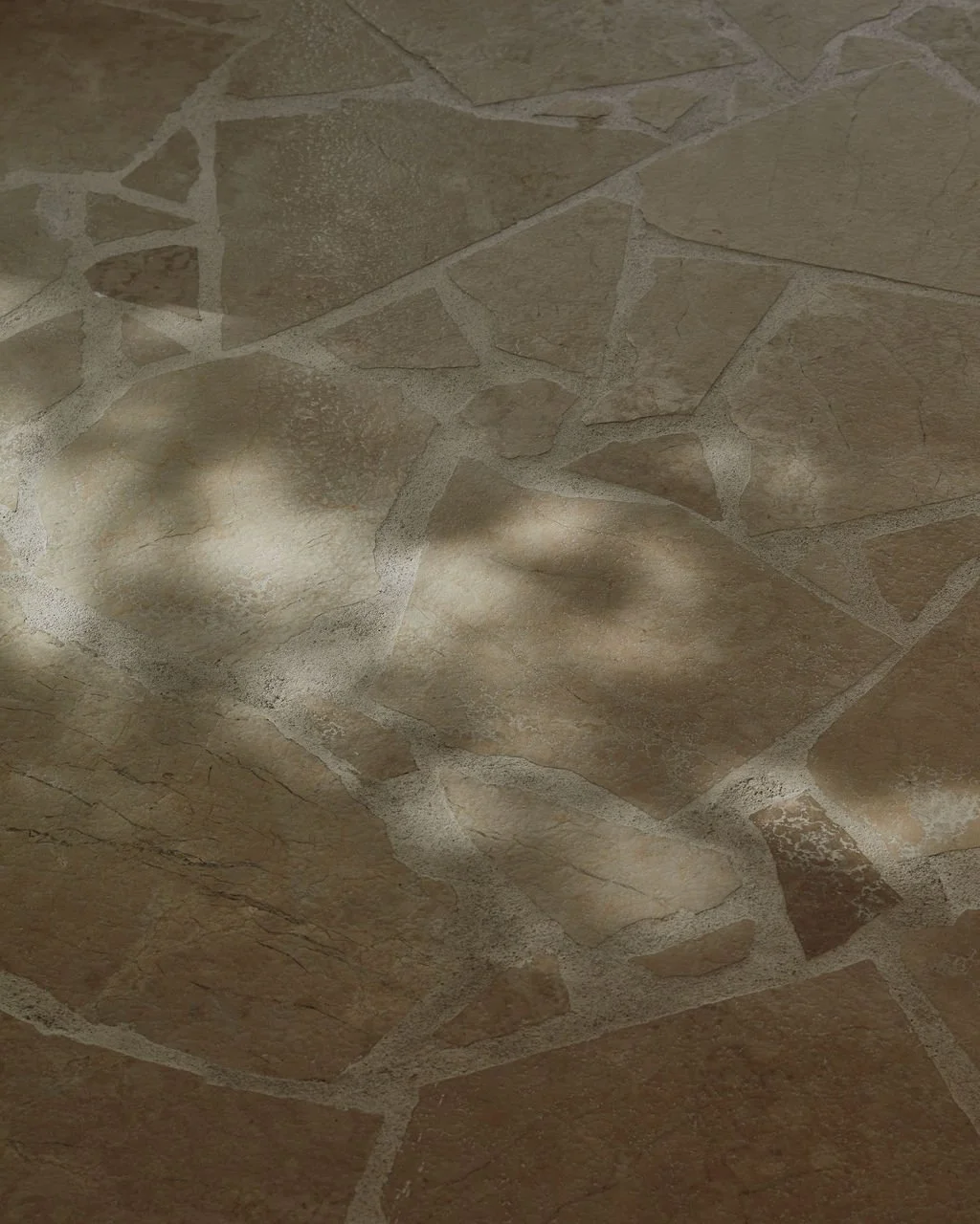 An abstract detail shot within Lune Loft focusing on the irregular organic marble stone floor