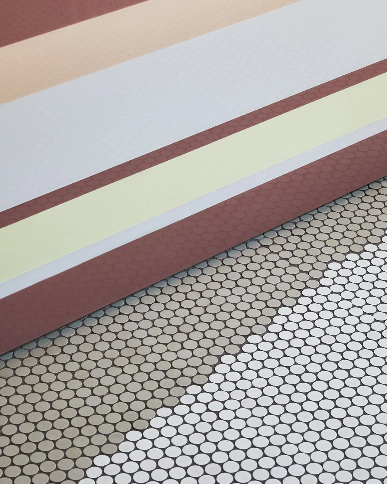 Close-up of a multi-colored, mosaic-tiled floor with a step covered in pastel-colored panels.