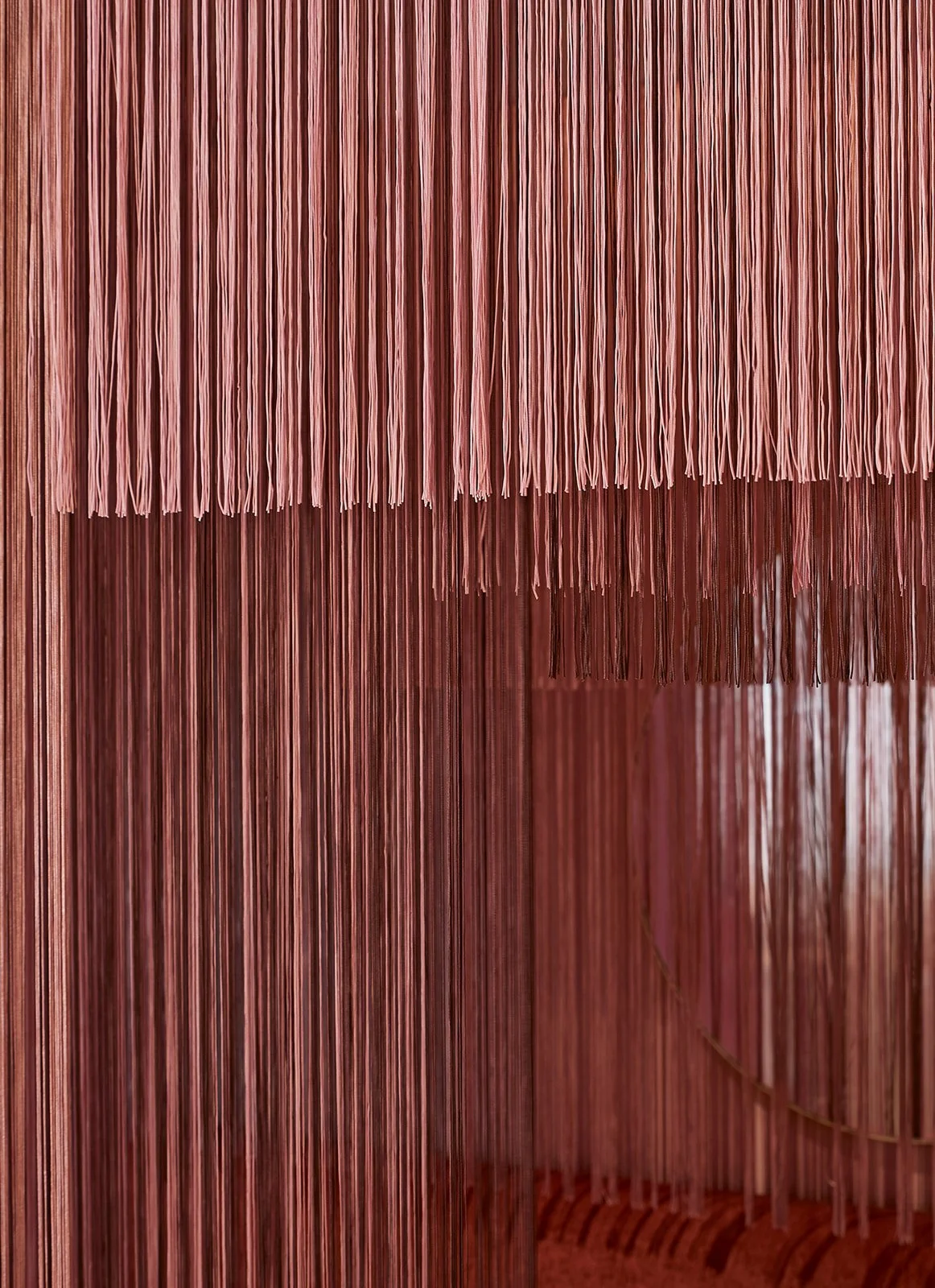 Pink vertical fringed curtains or decor panels.