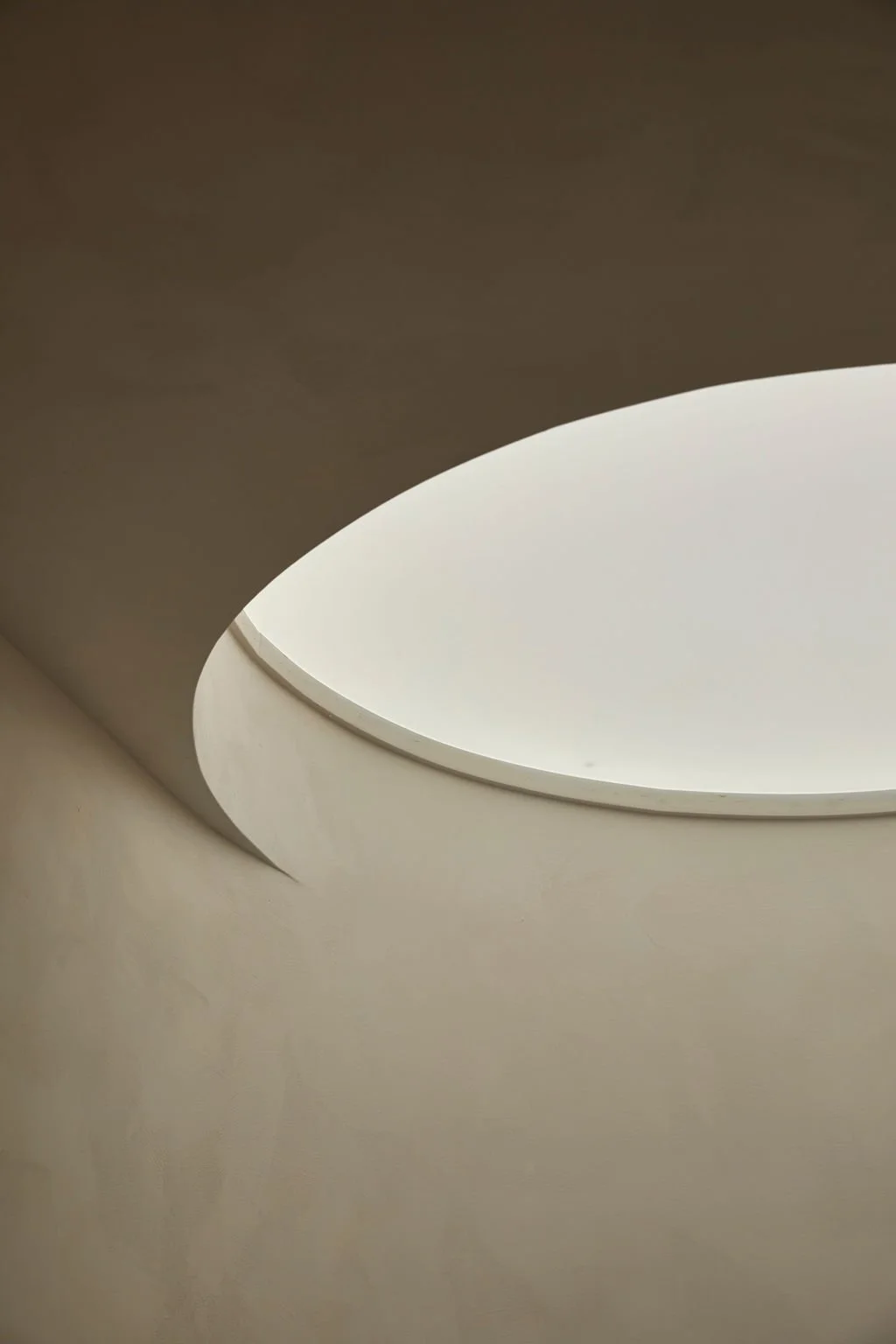A close-up architectural detail of a curved, hand-troweled plaster ceiling cutout catching soft natural light in a bespoke hospitality interior.