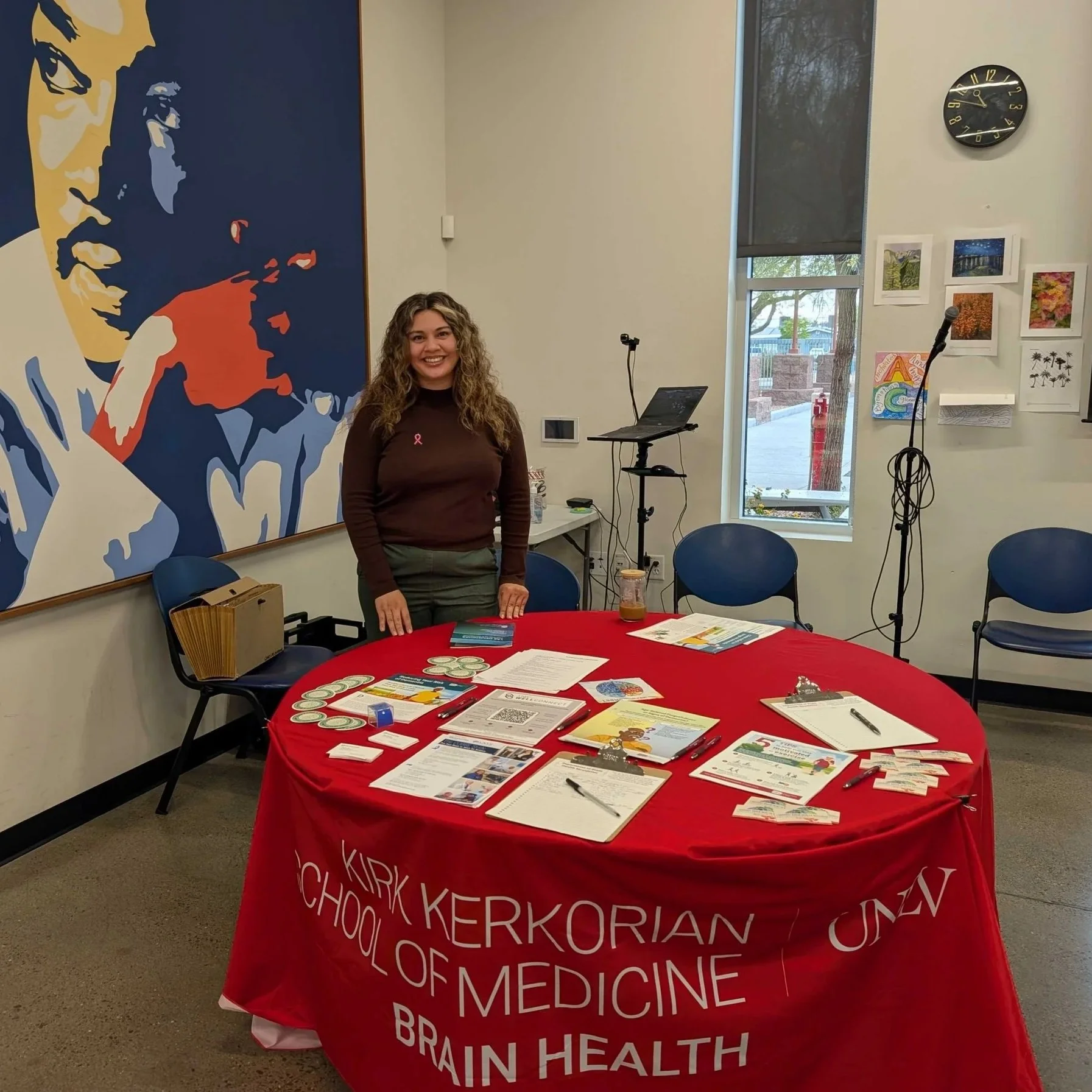 Image of Staff member Kim Cobos behind a table with resources on it.