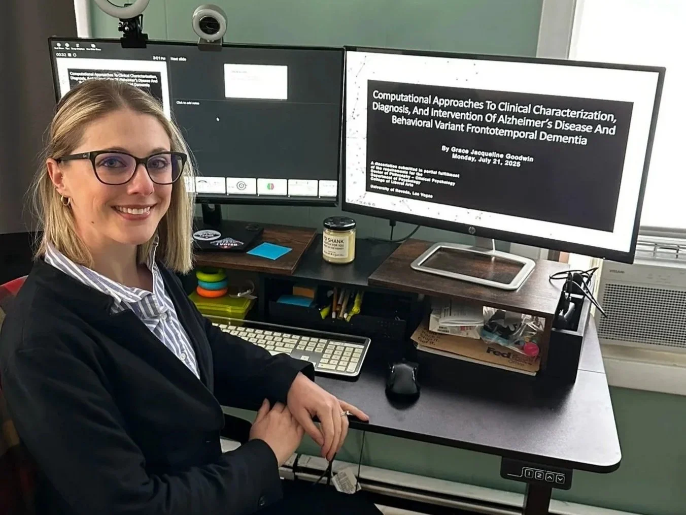 Grace sitting in front of multiple computer screens as she presents her dissertation to her committee virtually
