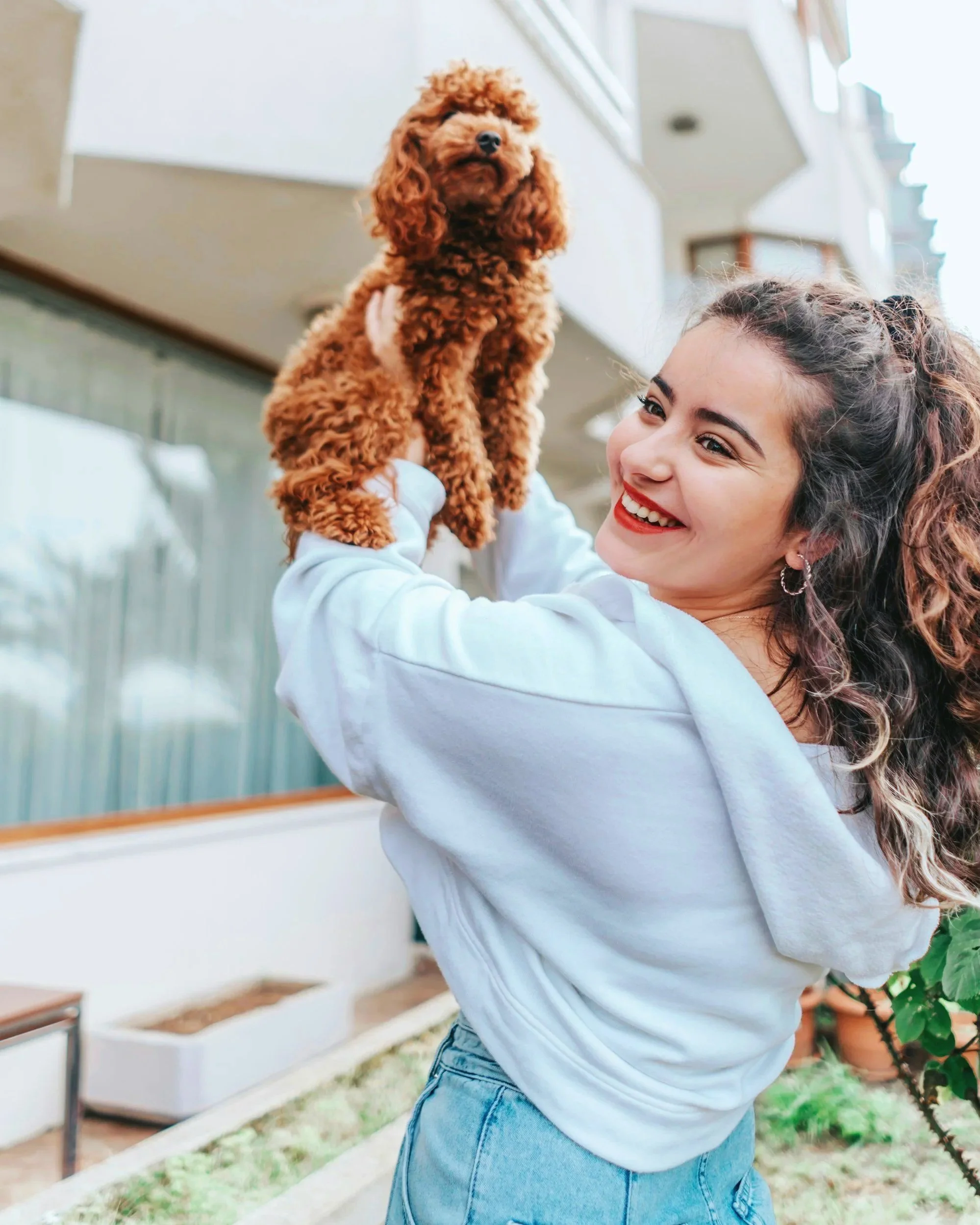 A young, smiling woman holds up a cute dog
